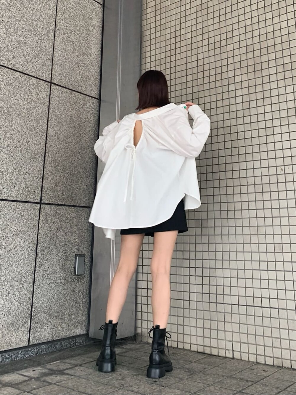 ブラック系のブーツ、ブラック系のスカート、ホワイト系のシャツ/ブラウスを着用したレディースの夏コーディネートの2枚目の写真