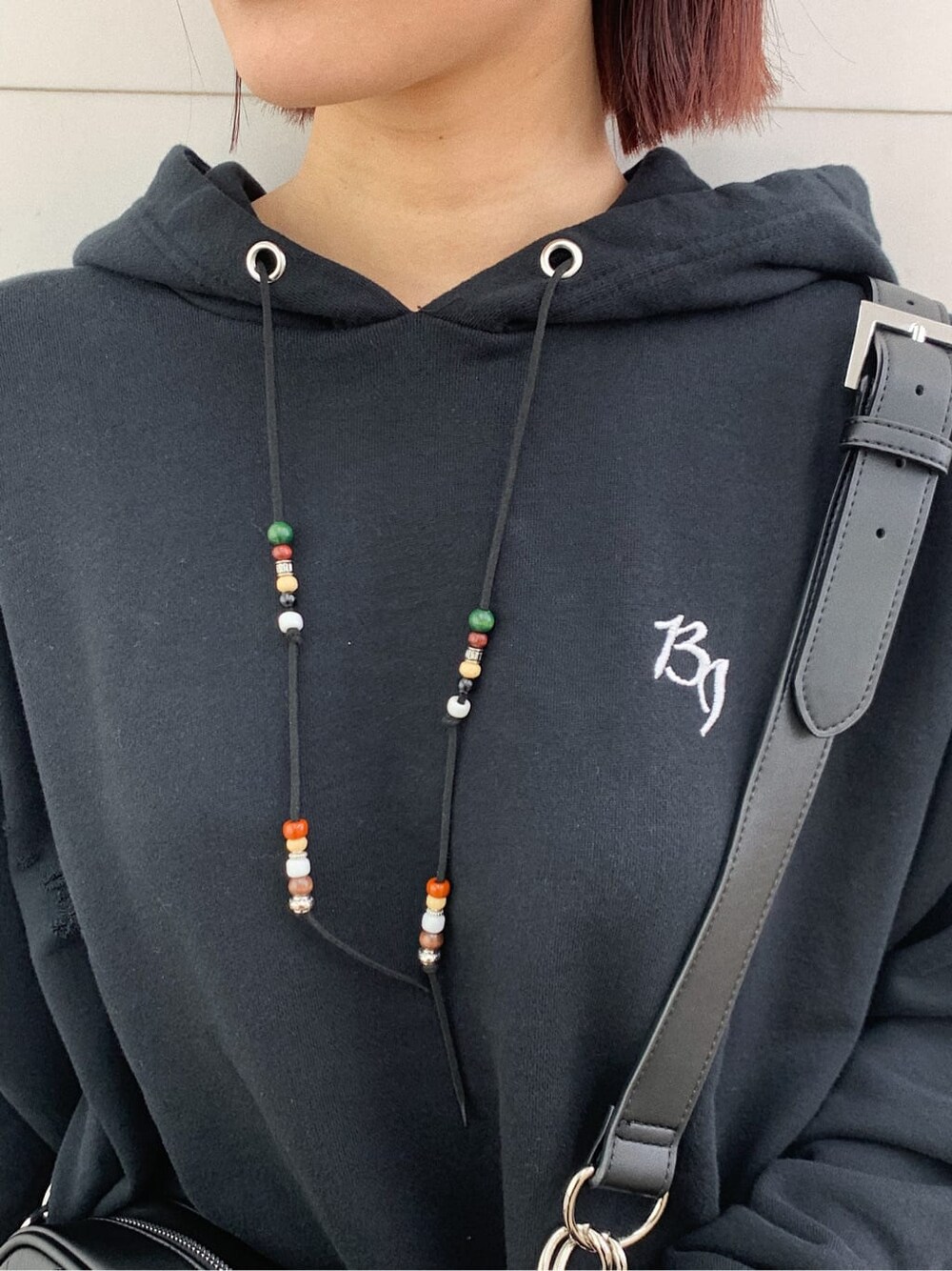 ブラック系のショルダーバッグ、ブラック系のブーツ、ブラック系のパーカーを着用したレディースの秋コーディネートの3枚目の写真