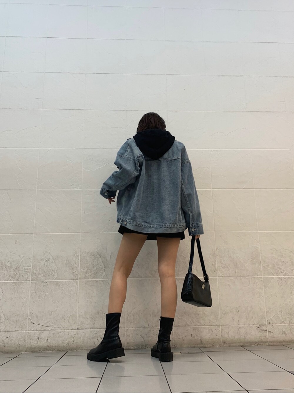 ブルー系のデニムジャケット、ブラック系のスカート、ブラック系のショルダーバッグを着用したレディースの春コーディネートの4枚目の写真