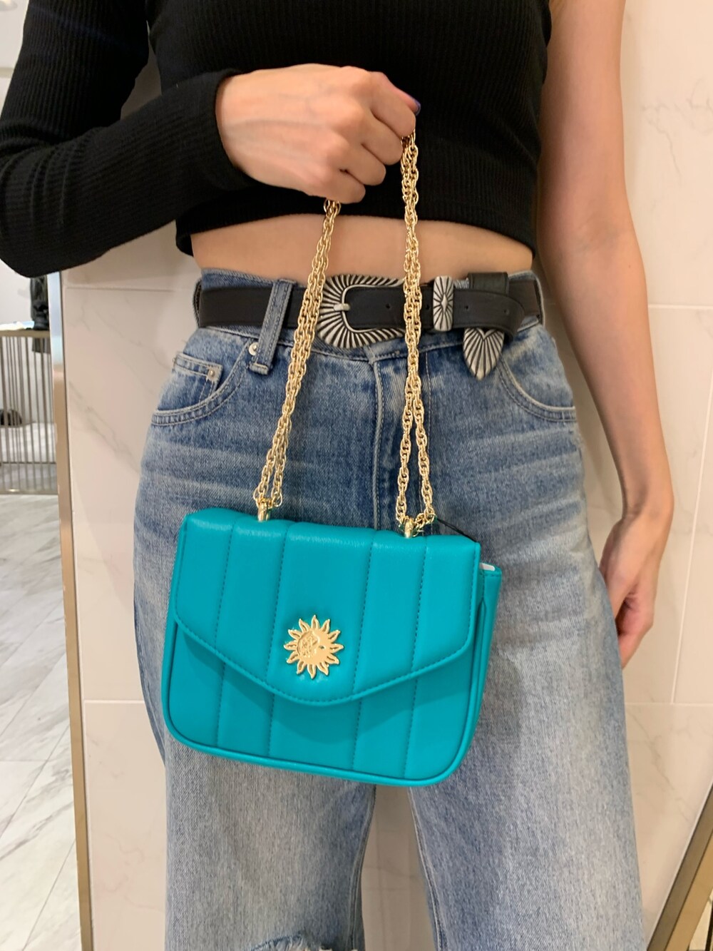 ブラック系のブーツ、ブルー系のデニムパンツ、ブルー系のショルダーバッグを着用したレディースの夏コーディネートの6枚目の写真