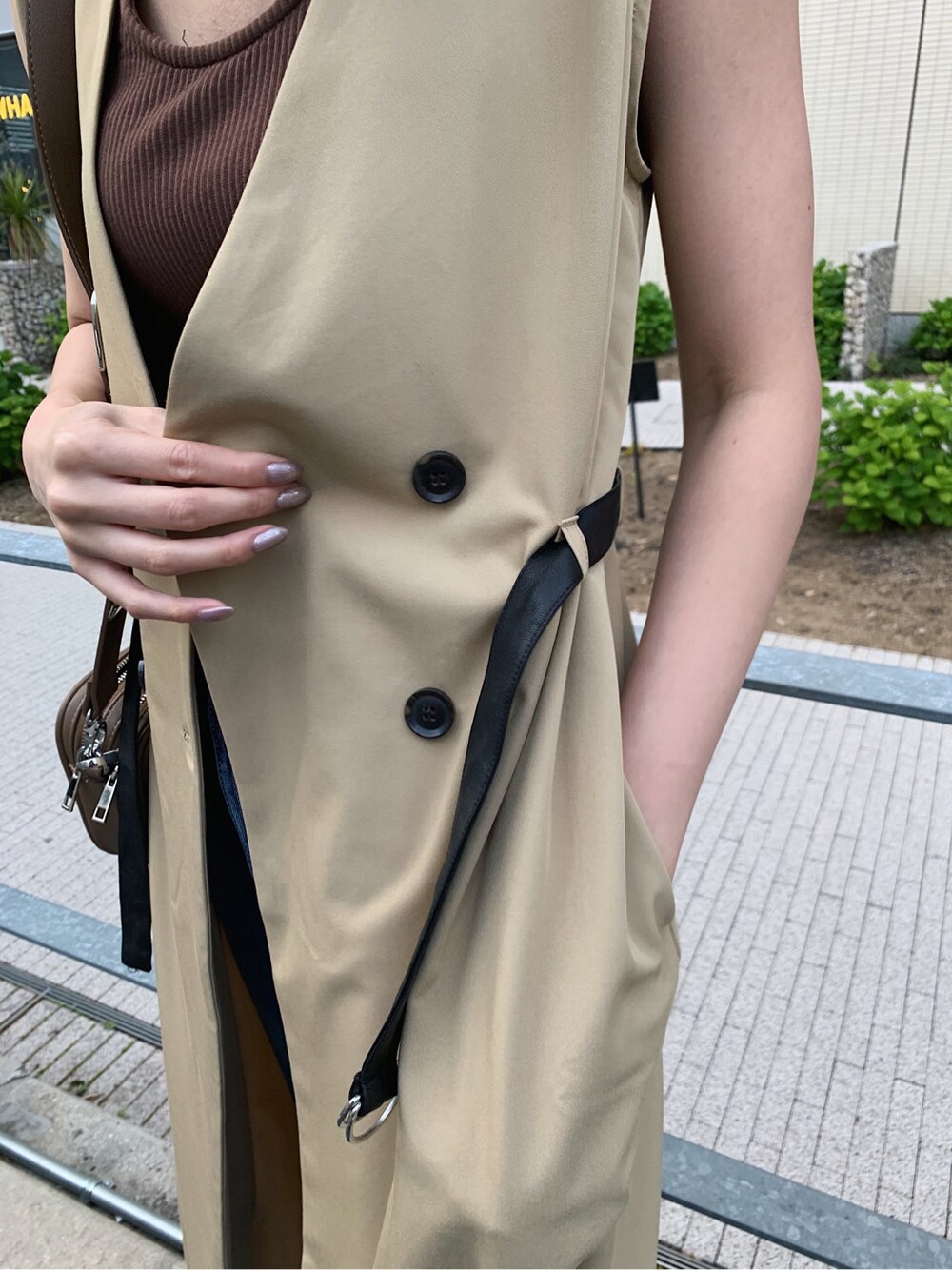 ブルー系のデニムパンツ、ベージュ系のトレンチコート、ブラウン系のタンクトップを着用したレディースの春コーディネートの4枚目の写真