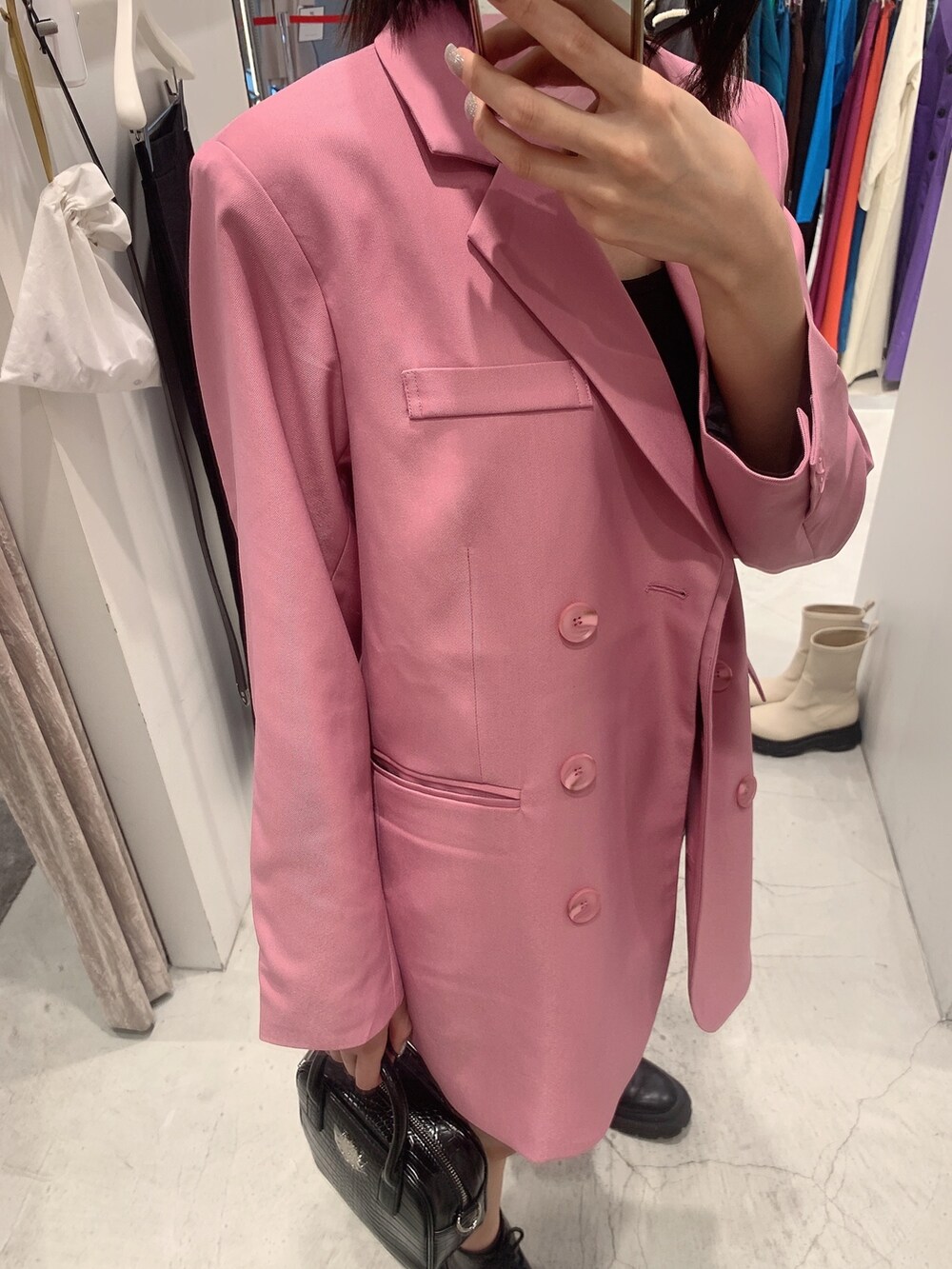 ピンク系のテーラードジャケット、ホワイト系のスカート、ブラック系のショルダーバッグを着用したレディースの冬コーディネートの4枚目の写真