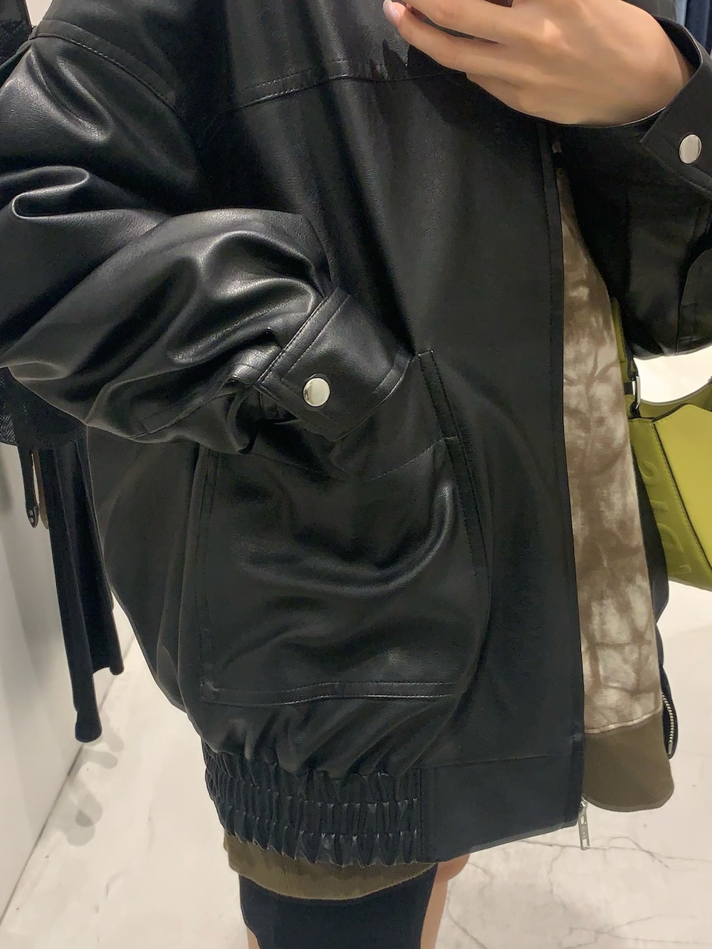 ブラック系のブーツ、ブラック系のハンドバッグ、ブラック系のブルゾンを着用したレディースの秋コーディネートの4枚目の写真