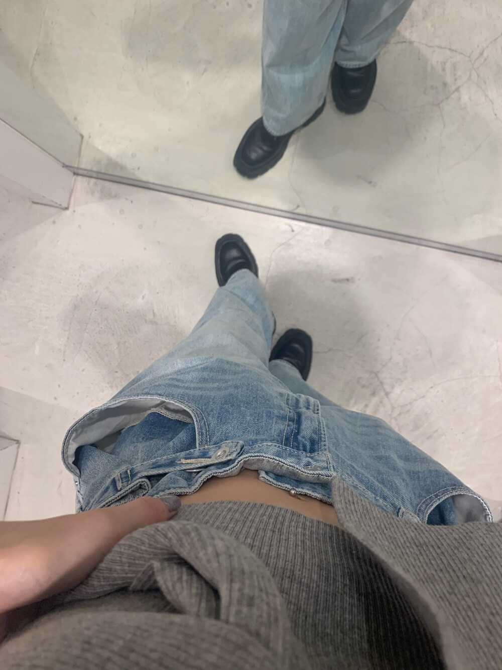 ブルー系のデニムパンツ、ブラック系のブーツ、グレー系のチューブトップを着用したレディースの春コーディネートの7枚目の写真