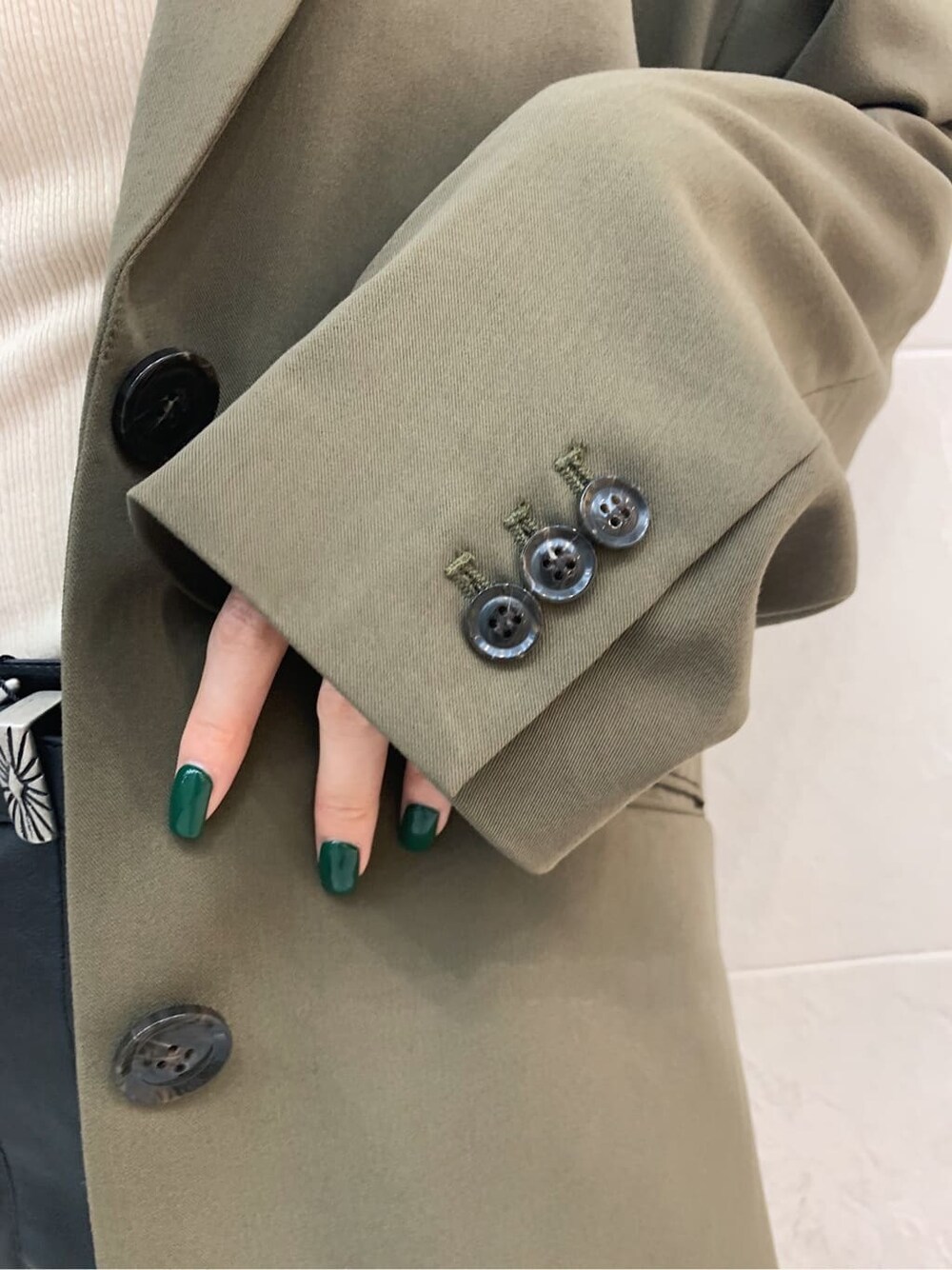 ホワイト系のキャミソール、ベージュ系のテーラードジャケット、ブラック系のブーツを着用したレディースの秋コーディネートの4枚目の写真