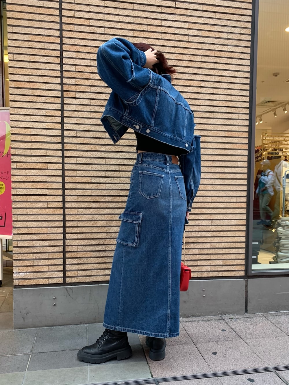 ブルー系のデニムジャケット、ブルー系のデニムスカート、レッド系のショルダーバッグを着用したレディースの秋コーディネートの3枚目の写真