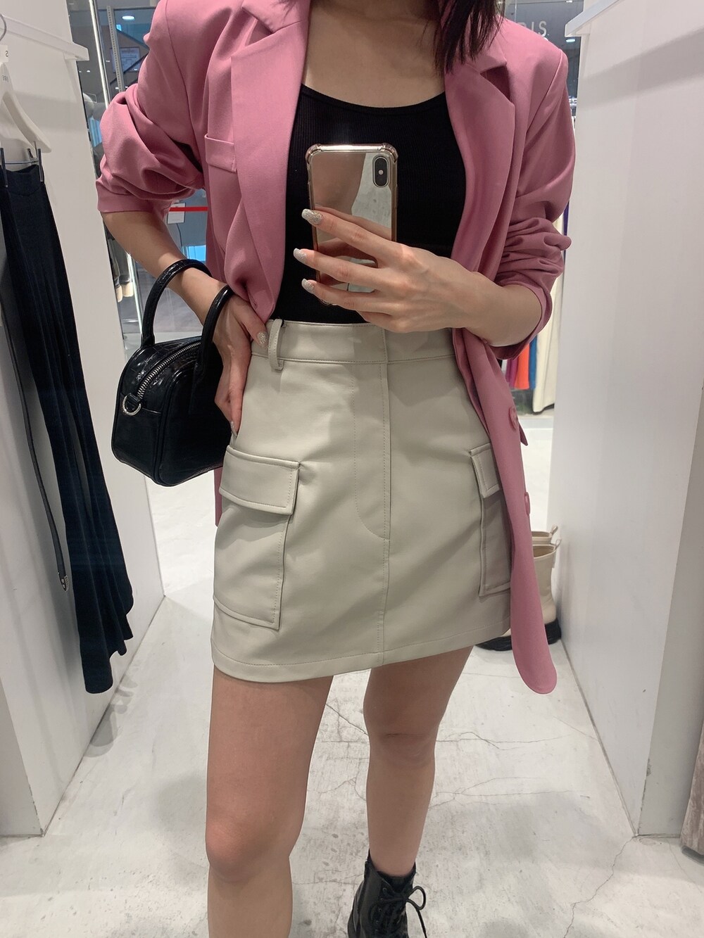 ピンク系のテーラードジャケット、ホワイト系のスカート、ブラック系のショルダーバッグを着用したレディースの冬コーディネートの7枚目の写真