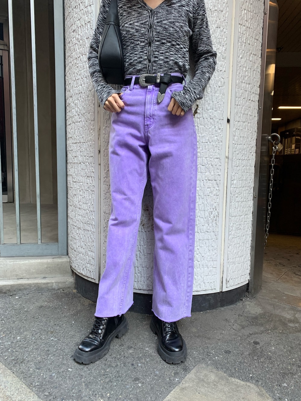 パープル系のデニムパンツ、ブラック系のニット/セーター、ブラック系のハンドバッグを着用したレディースの冬コーディネートの8枚目の写真
