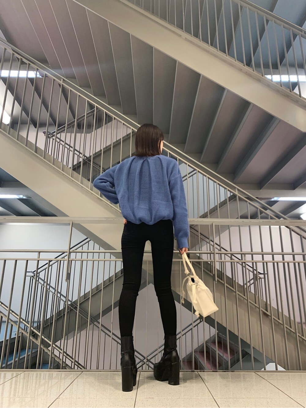 ブラック系のデニムパンツ、ホワイト系のショルダーバッグ、ブルー系のニット/セーターを着用したレディースの冬コーディネートの5枚目の写真