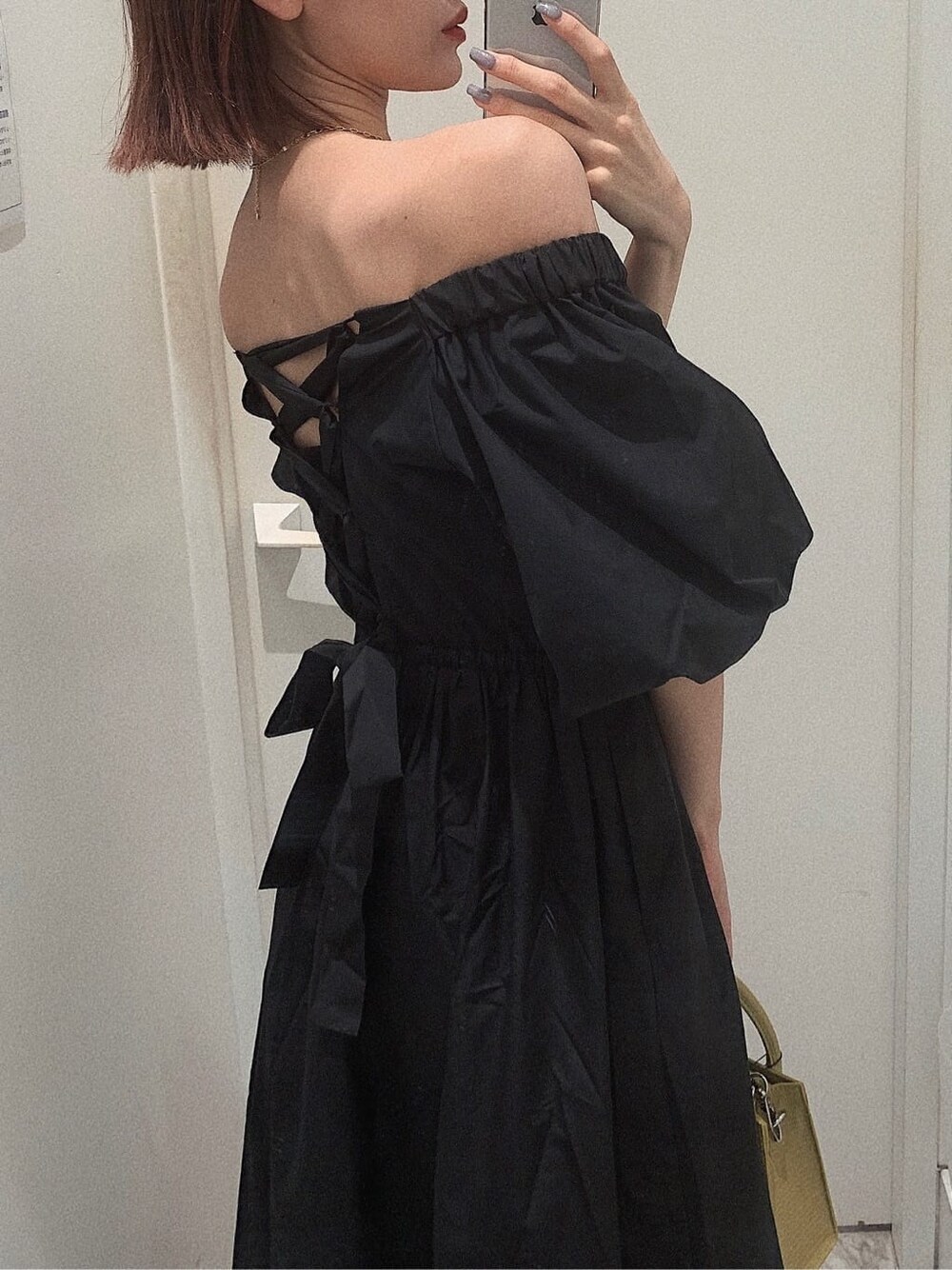 ブラック系のブーツ、イエロー系のショルダーバッグ、ブラック系のワンピースを着用したレディースの春コーディネートの5枚目の写真