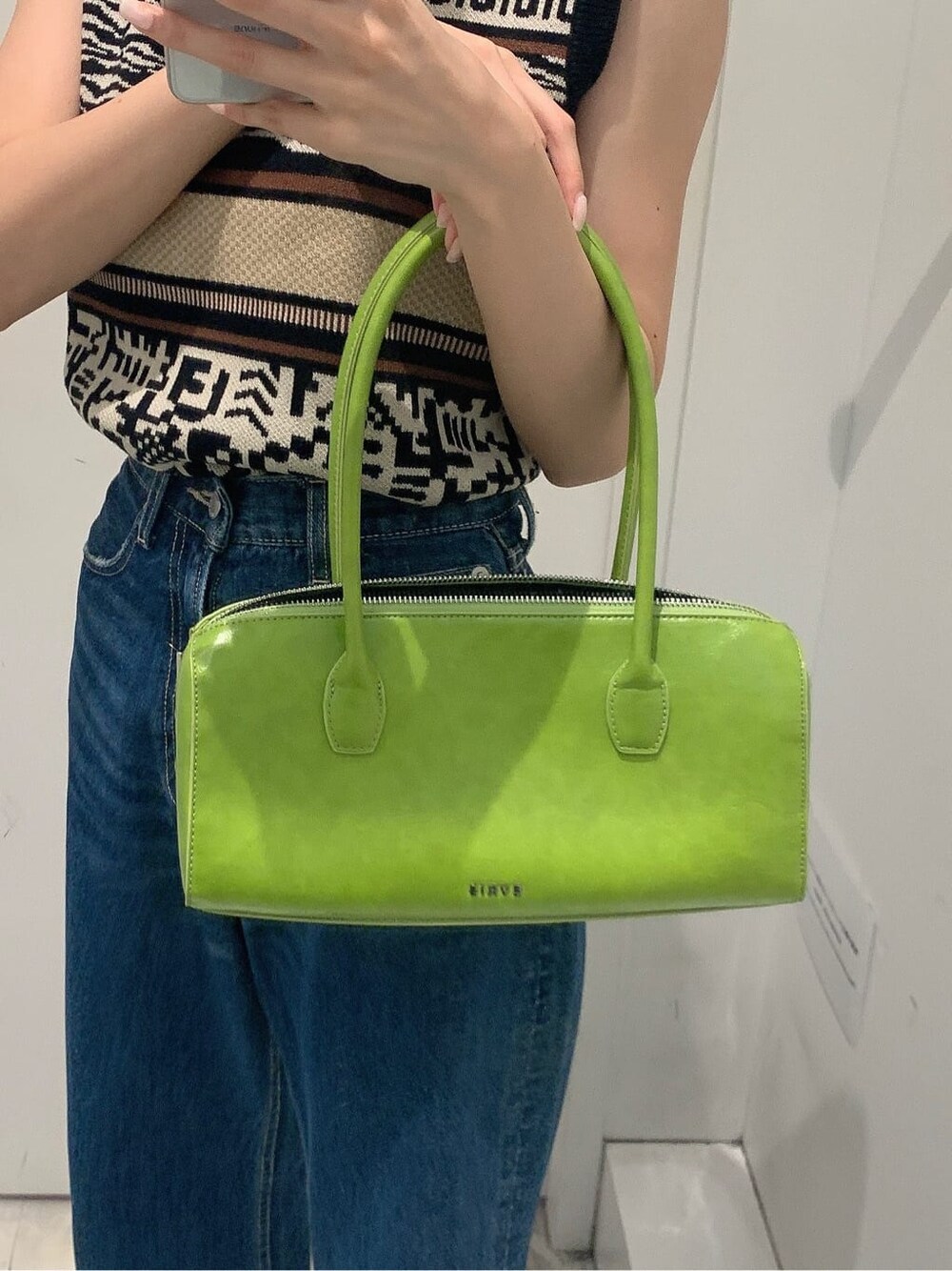 グリーン系のボストンバッグ、ブルー系のデニムパンツ、ブラック系のタンクトップを着用したレディースの夏コーディネートの6枚目の写真