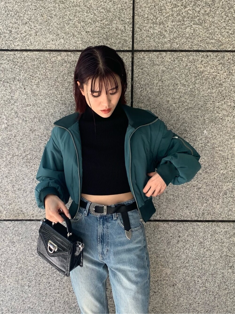 ブラック系のハンドバッグ、ブルー系のデニムパンツ、ブルー系のMA-1を着用したレディースの秋コーディネートの4枚目の写真