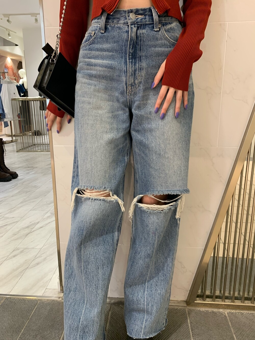 レッド系のニット/セーター、ブラック系のショルダーバッグ、ブルー系のデニムパンツを着用したレディースの夏コーディネートの9枚目の写真