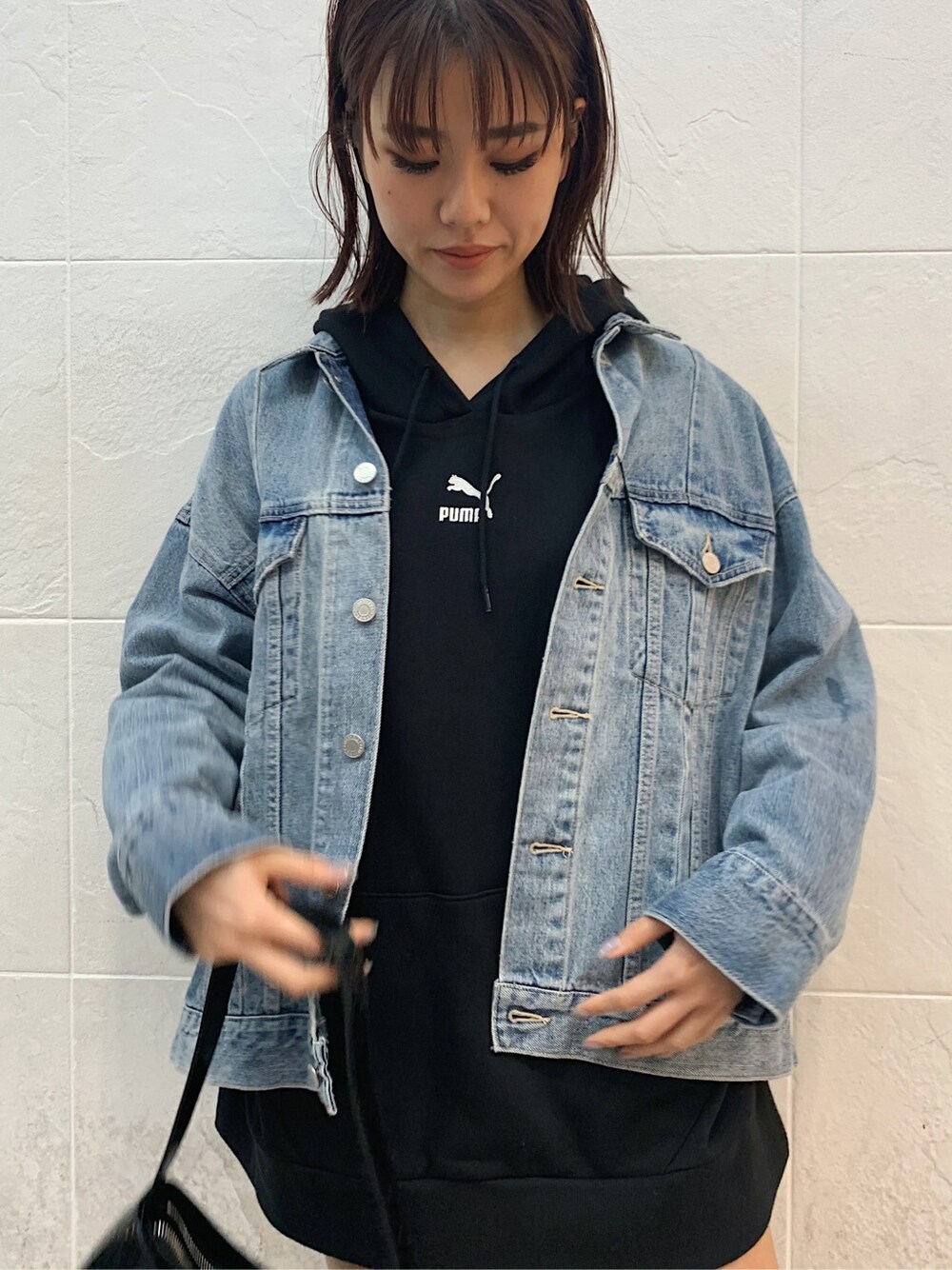 ブルー系のデニムジャケット、ブラック系のスカート、ブラック系のショルダーバッグを着用したレディースの春コーディネートの6枚目の写真