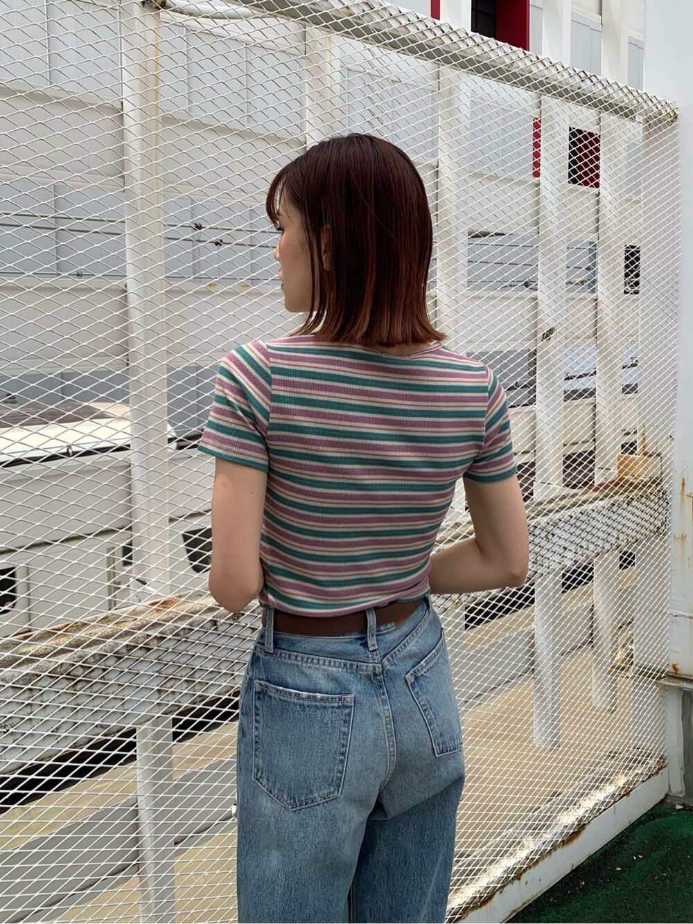 ブラウン系のサンダル、ブルー系のデニムパンツ、ホワイト系のショルダーバッグを着用したレディースの夏コーディネートの4枚目の写真