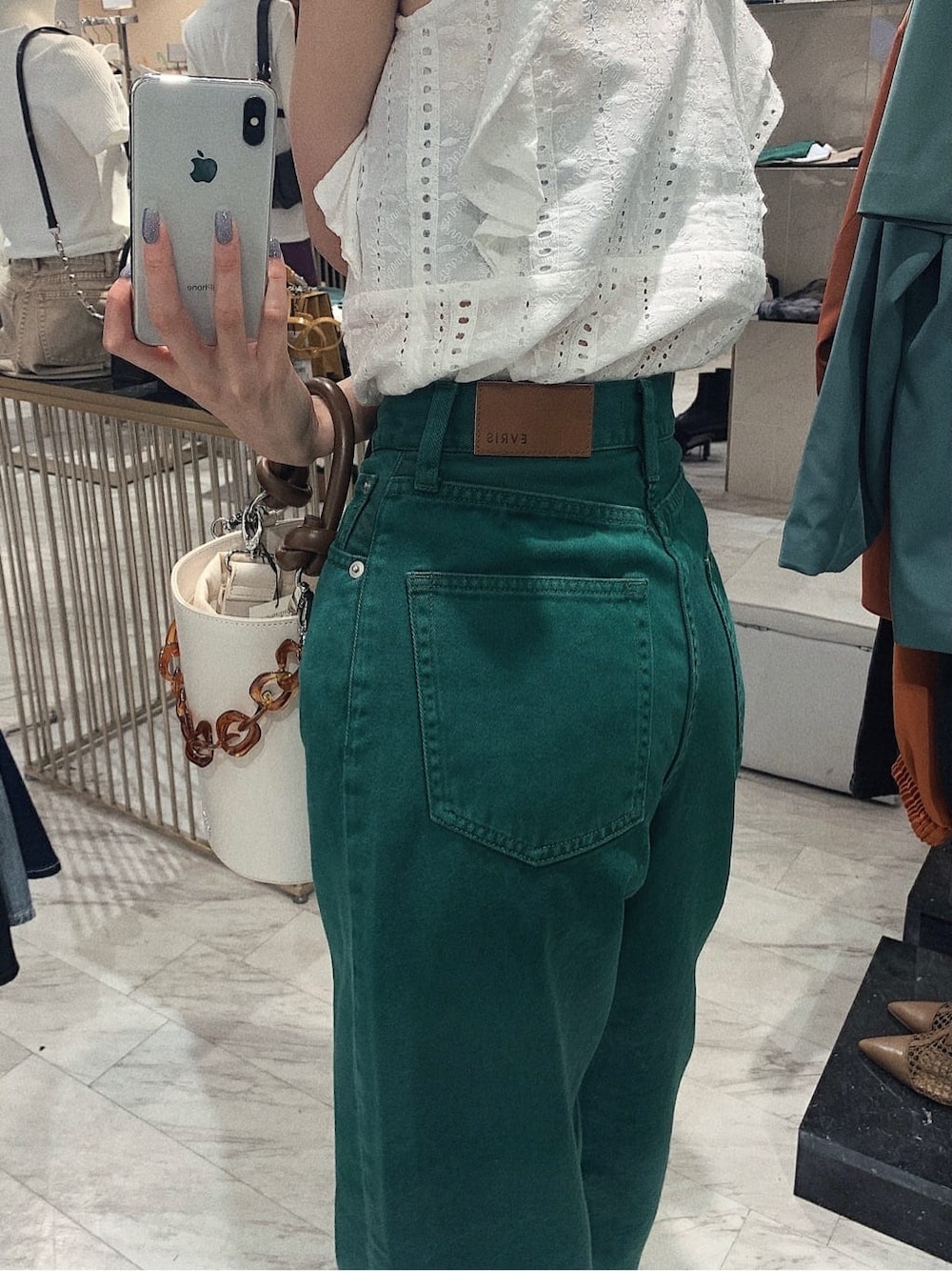 グリーン系のデニムパンツ、ホワイト系のタンクトップ、ホワイト系のサンダルを着用したレディースの春コーディネートの6枚目の写真