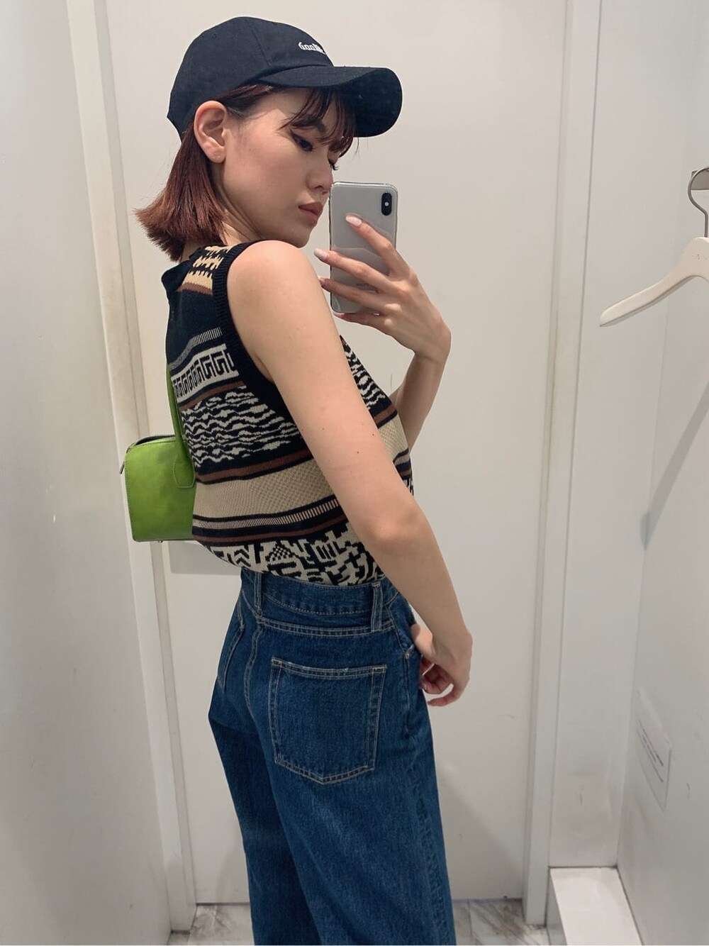 グリーン系のボストンバッグ、ブルー系のデニムパンツ、ブラック系のタンクトップを着用したレディースの夏コーディネートの4枚目の写真