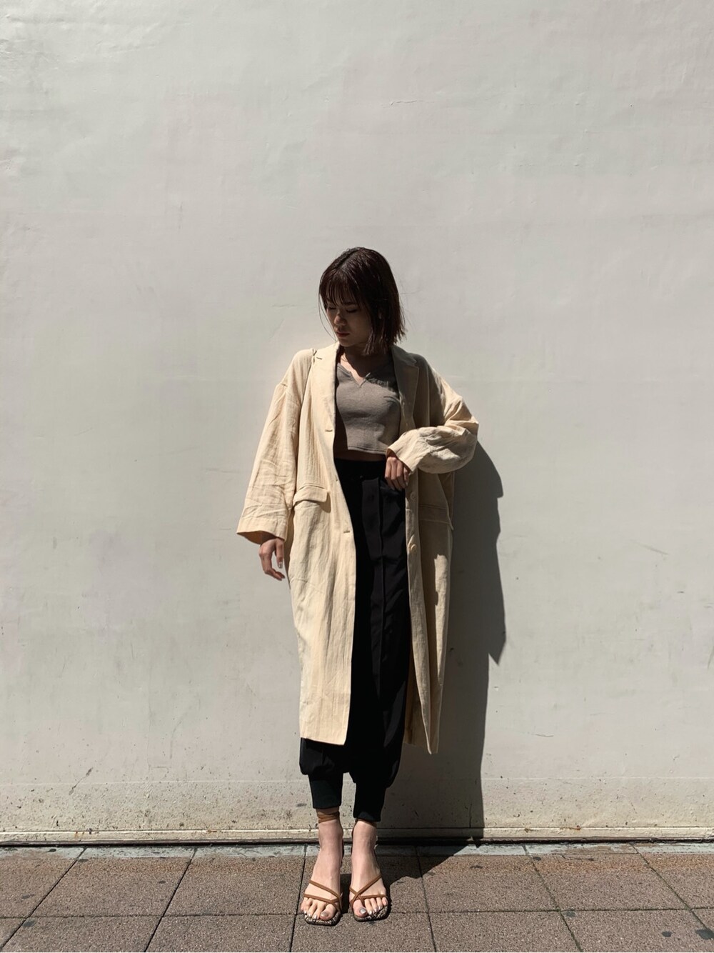 ベージュ系のチェスターコート、ブラック系のその他パンツ、ブラウン系のサンダルを着用したレディースの春コーディネートの3枚目の写真