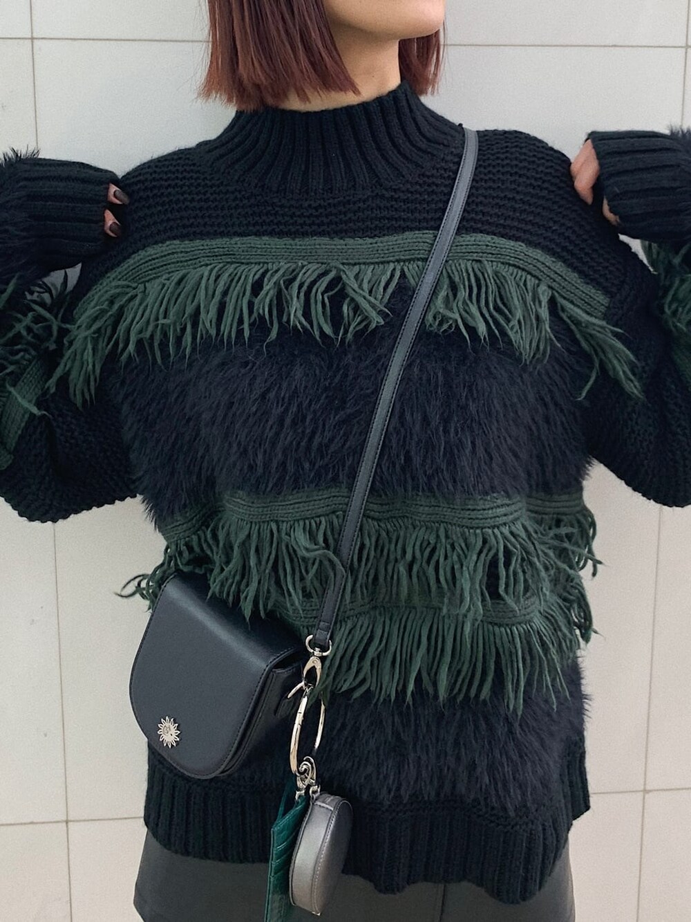 ブラック系のショルダーバッグ、ブラック系のブーツ、ブラック系のスカートを着用したレディースの冬コーディネートの3枚目の写真