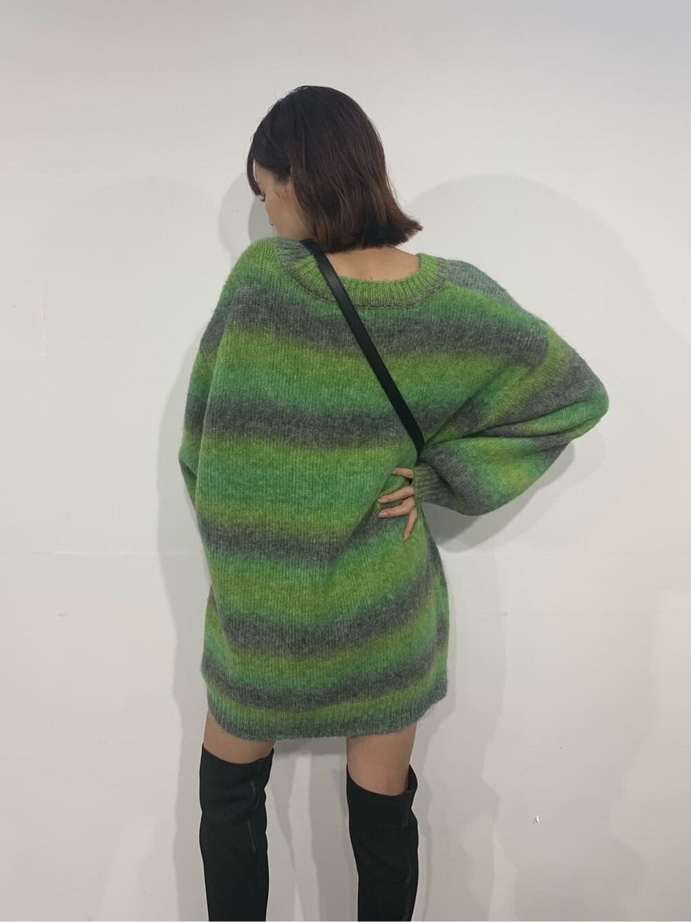 グリーン系のカーディガン/ボレロ、ブラック系のブーツ、ブラック系のショルダーバッグを着用したレディースの秋コーディネートの5枚目の写真