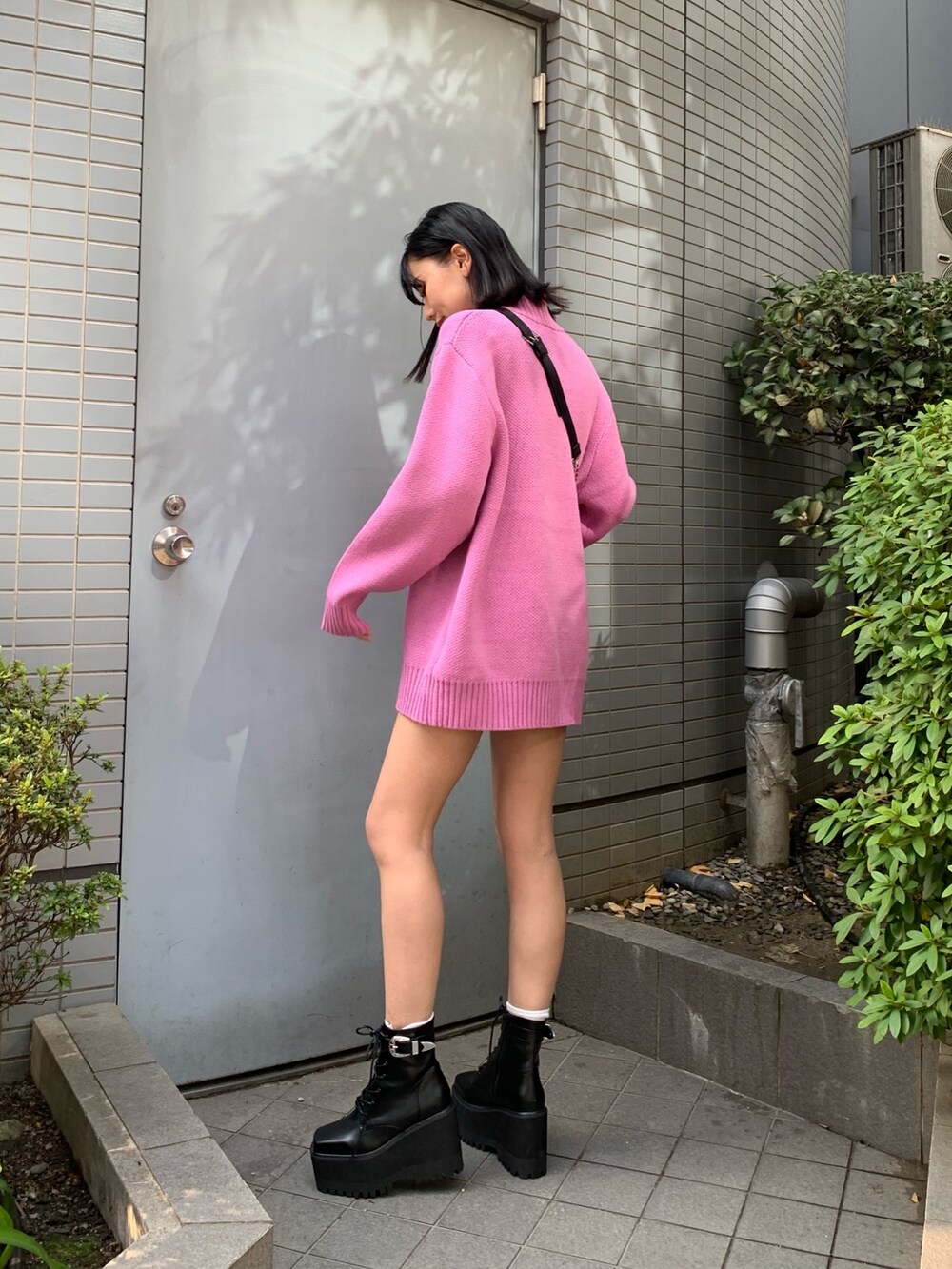 ピンク系のニット/セーター、ブラック系のブーツ、ブラック系のボディバッグ/ウエストポーチを着用したレディースの冬コーディネートの3枚目の写真