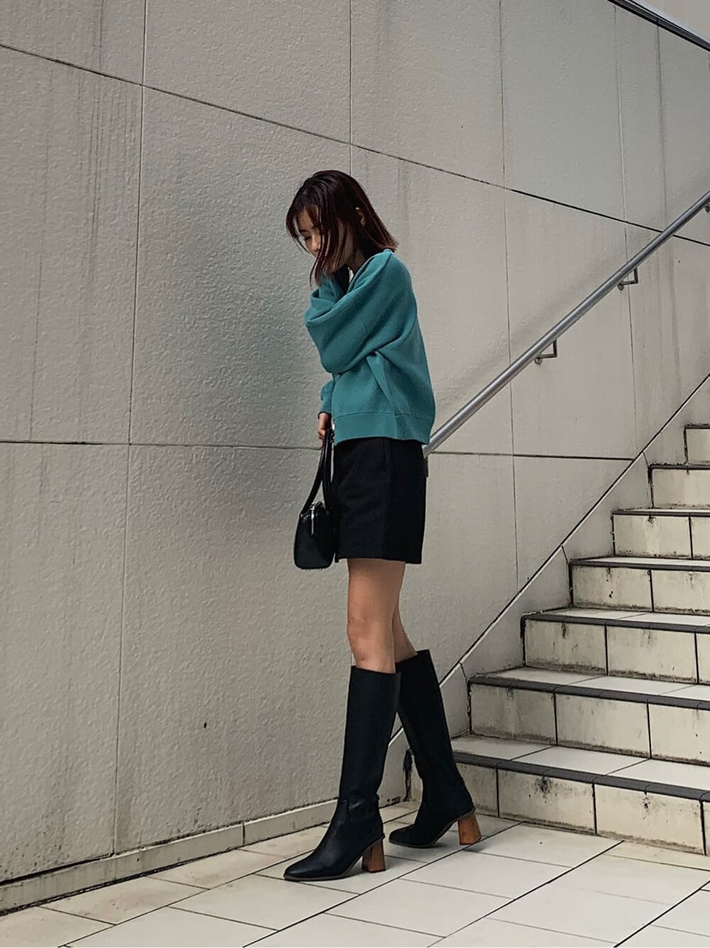 ブラック系のブーツ、ブラック系のスカート、ホワイト系のキャミソールを着用したレディースの冬コーディネートの2枚目の写真