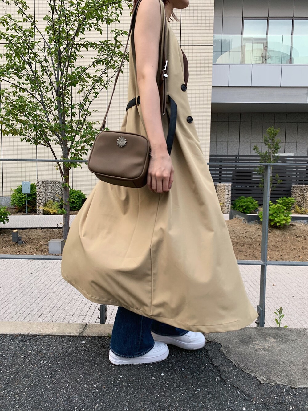 ブルー系のデニムパンツ、ベージュ系のトレンチコート、ブラウン系のタンクトップを着用したレディースの春コーディネートの5枚目の写真