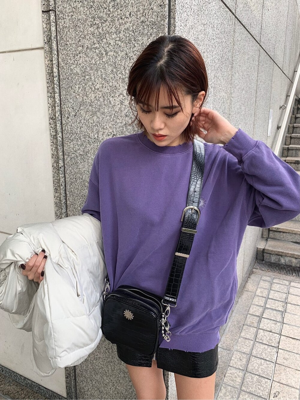 ホワイト系のダウンベスト、パープル系のスウェット、ブラック系のスカートを着用したレディースの秋コーディネートの5枚目の写真