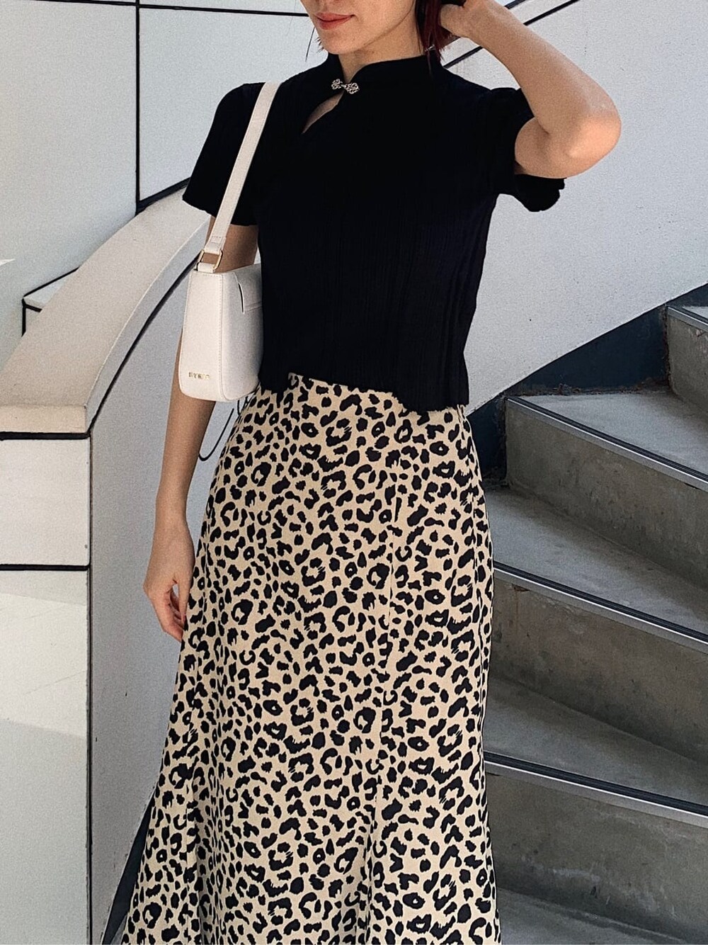 ブラック系のニット/セーター、ホワイト系のショルダーバッグ、その他のスカートを着用したレディースの春コーディネートの3枚目の写真