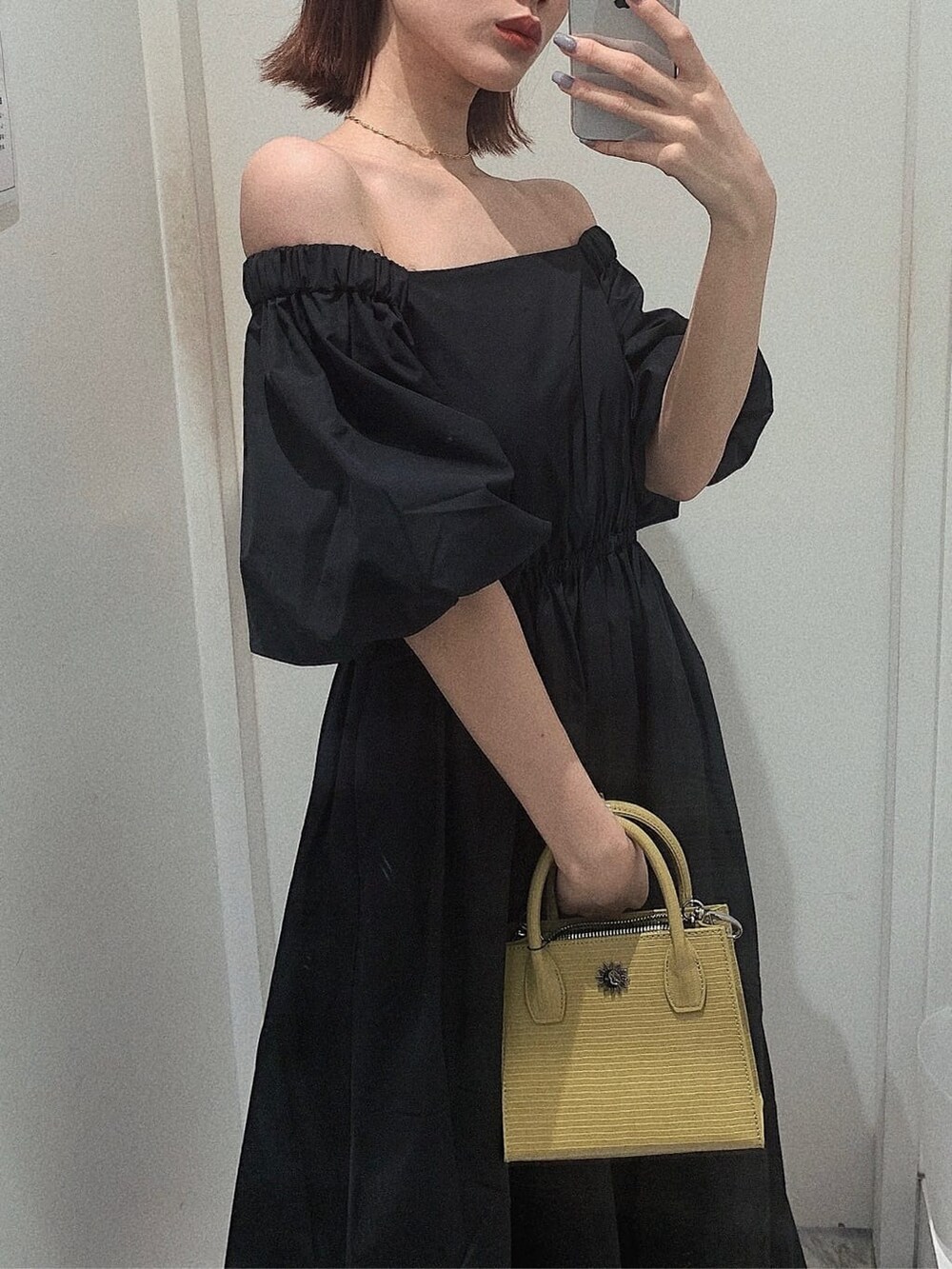 ブラック系のブーツ、イエロー系のショルダーバッグ、ブラック系のワンピースを着用したレディースの春コーディネートの2枚目の写真