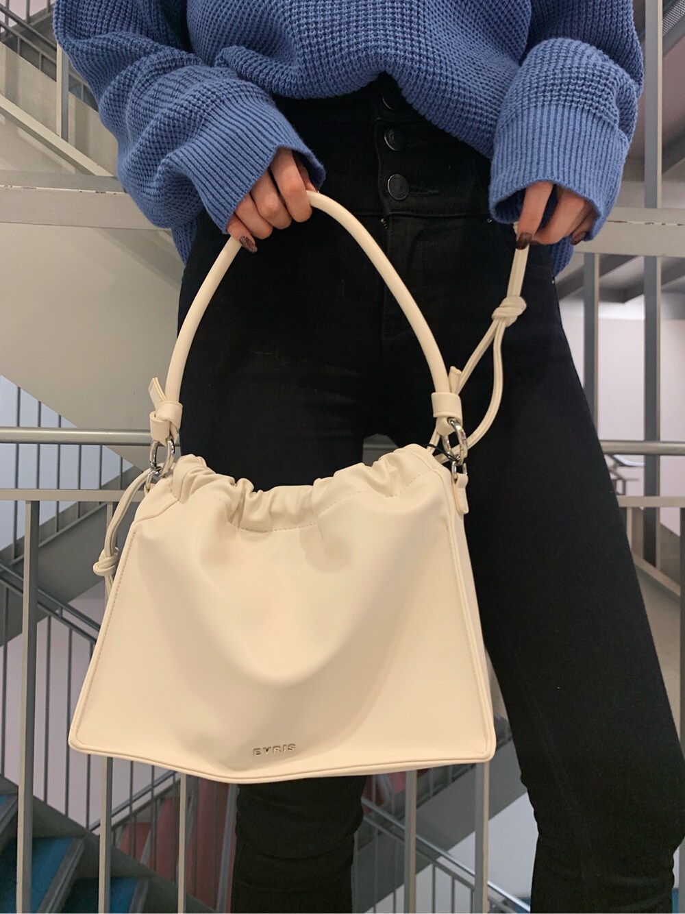 ブラック系のデニムパンツ、ホワイト系のショルダーバッグ、ブルー系のニット/セーターを着用したレディースの冬コーディネートの6枚目の写真