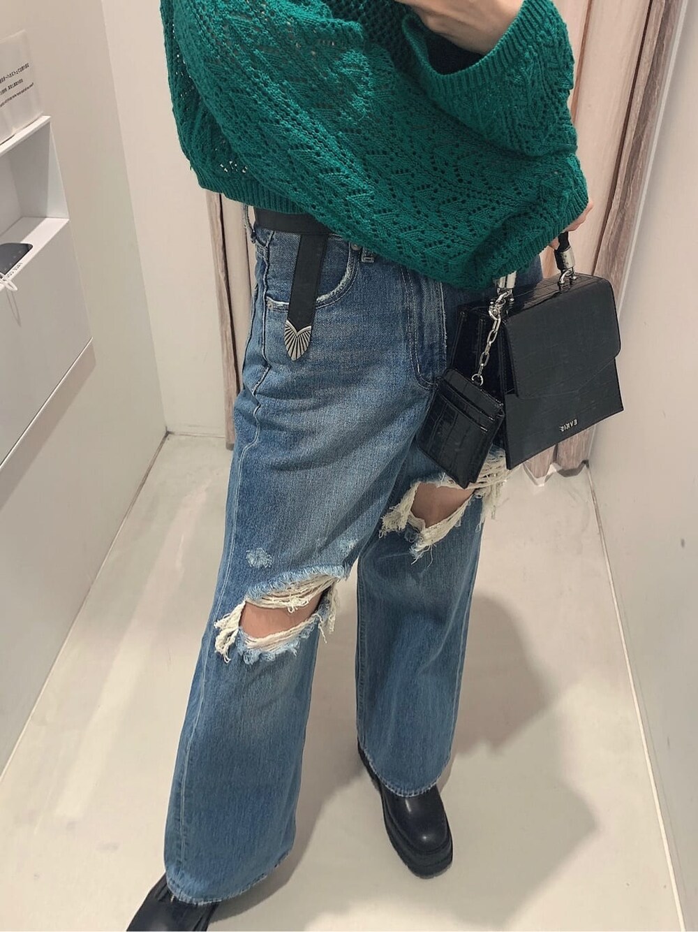 ブラック系のブーツ、ブルー系のデニムパンツ、グリーン系のニット/セーターを着用したレディースの春コーディネートの5枚目の写真