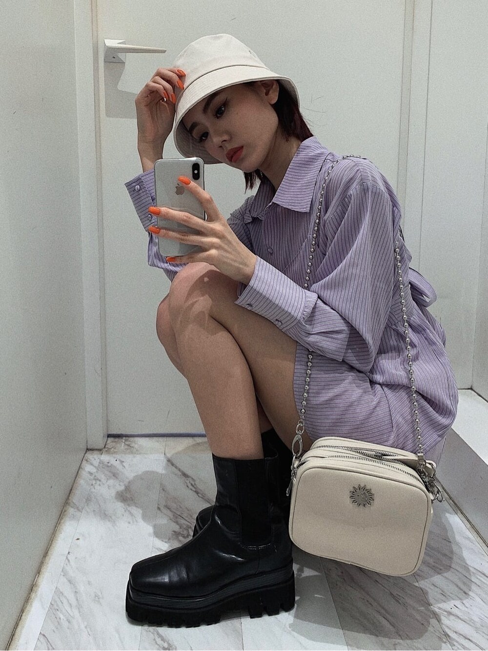 ホワイト系のスカート、ブラック系のブーツ、ホワイト系のショルダーバッグを着用したレディースの春コーディネートの10枚目の写真