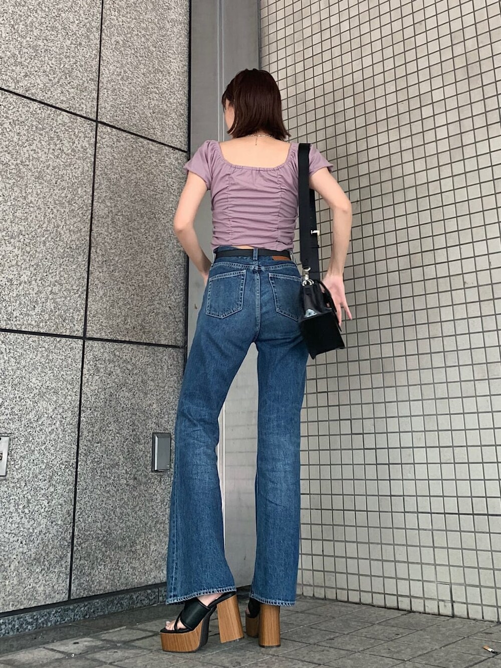 ブルー系のデニムパンツ、ブラック系のサンダル、ブラック系のベルトを着用したレディースの夏コーディネートの2枚目の写真