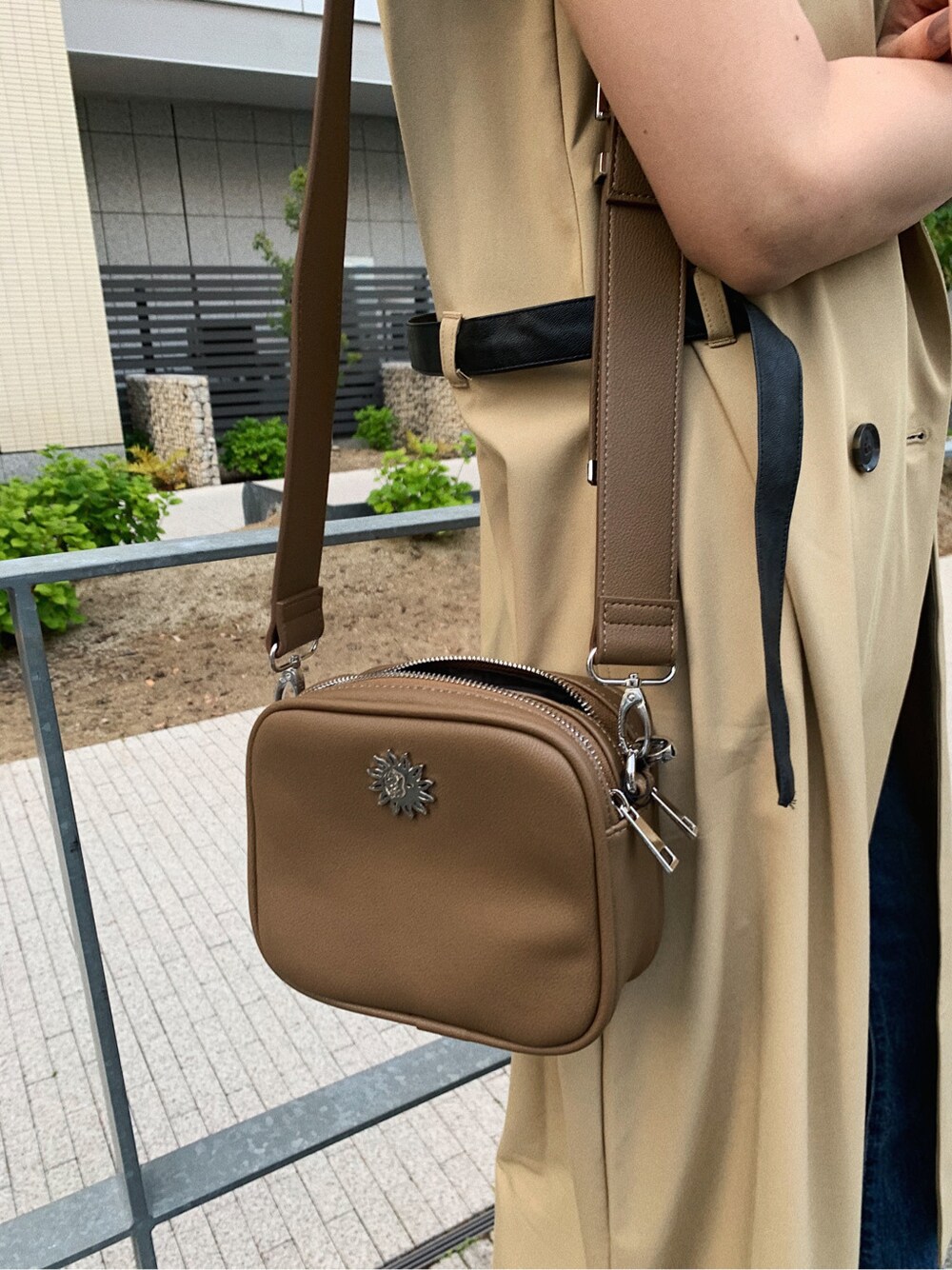 ブルー系のデニムパンツ、ベージュ系のトレンチコート、ブラウン系のタンクトップを着用したレディースの春コーディネートの9枚目の写真
