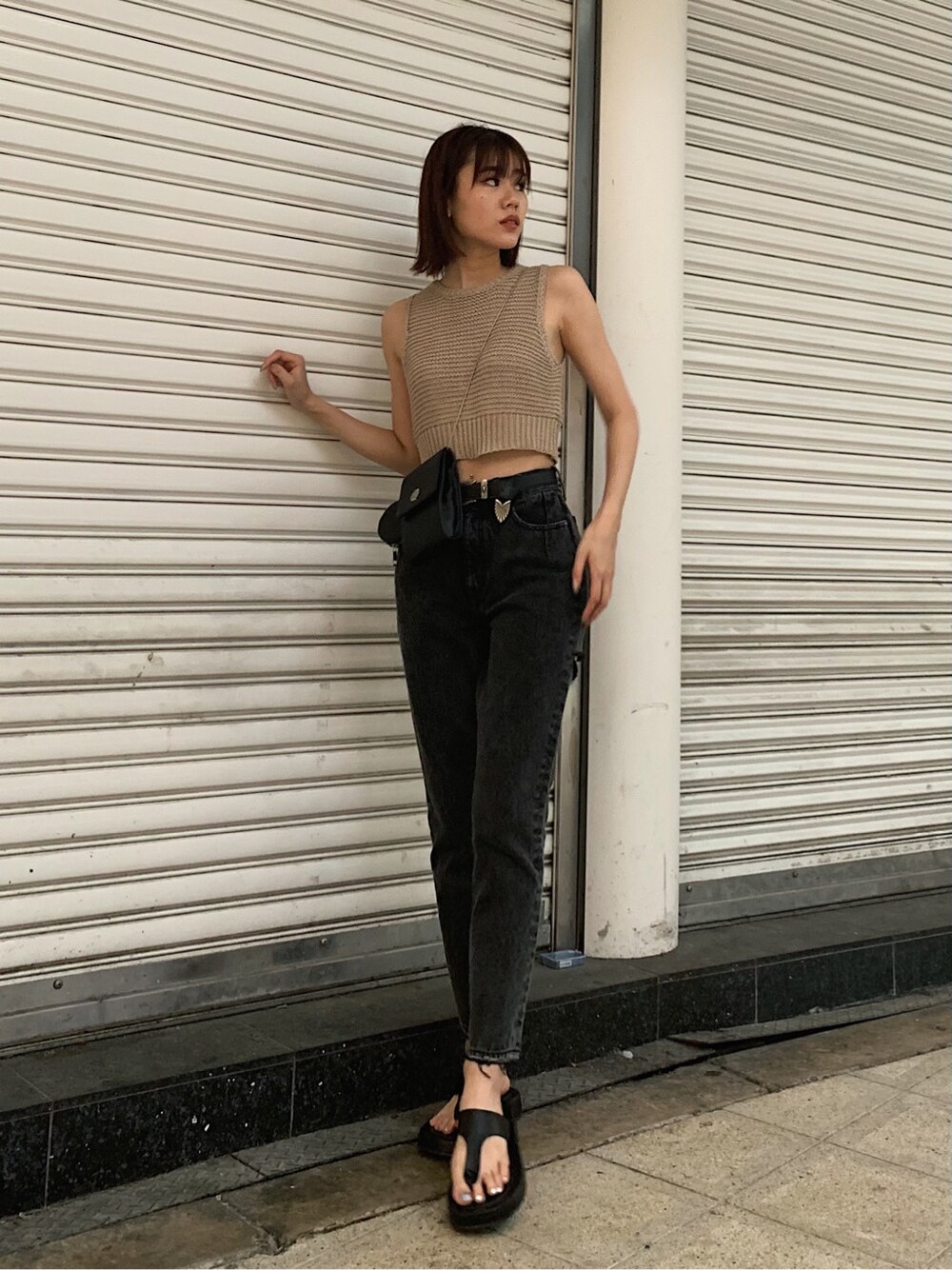 ブラック系のサンダル、ブラック系のデニムパンツ、ベージュ系のタンクトップを着用したレディースの春コーディネートの3枚目の写真