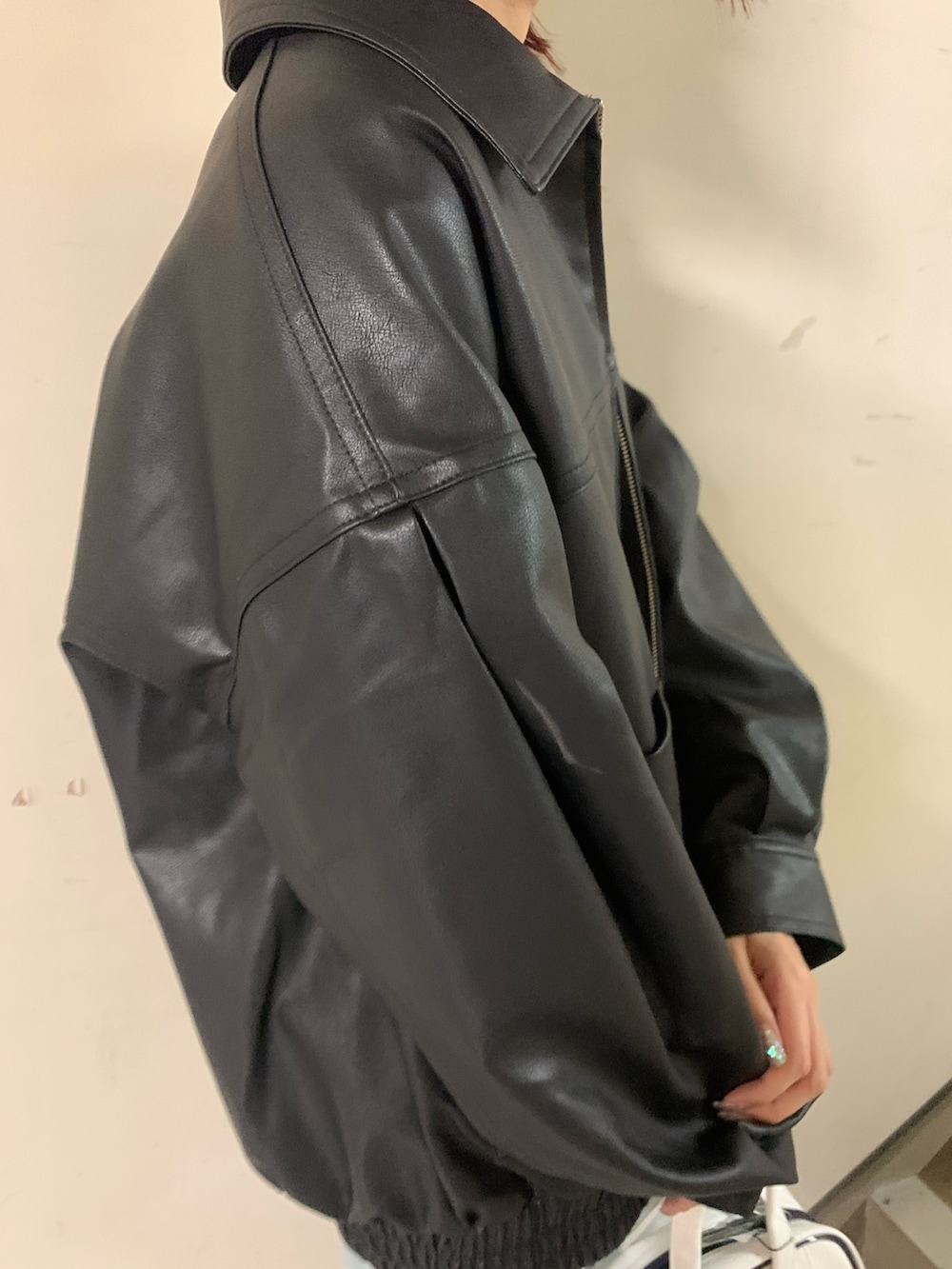 ホワイト系のニット/セーター、ブラック系のブルゾン、ブルー系のデニムパンツを着用したレディースの秋コーディネートの7枚目の写真