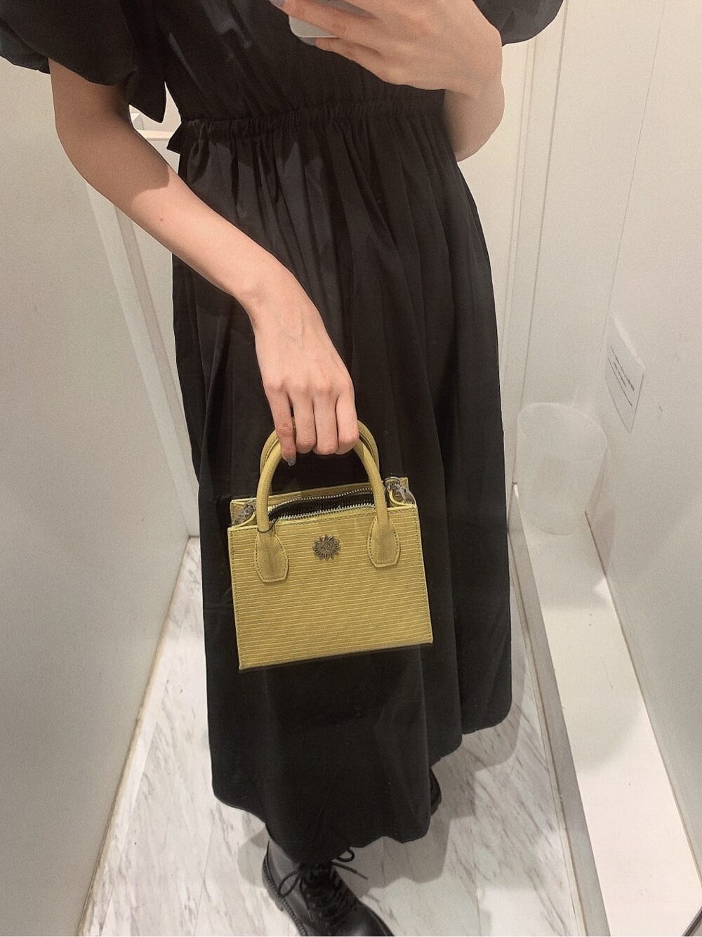 ブラック系のブーツ、イエロー系のショルダーバッグ、ブラック系のワンピースを着用したレディースの春コーディネートの7枚目の写真