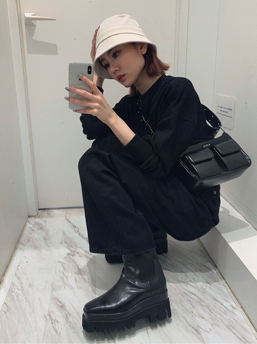 ブラック系のショルダーバッグ、ブラック系のカーディガン/ボレロ、ブラック系のブーツを着用したレディースの春コーディネートの9枚目の写真