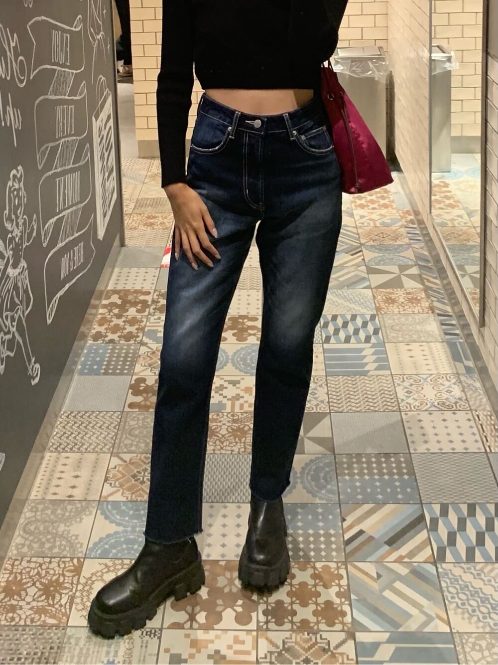 ブラック系のニット/セーター、ピンク系のハンドバッグ、ブルー系のデニムパンツを着用したレディースの秋コーディネートの4枚目の写真