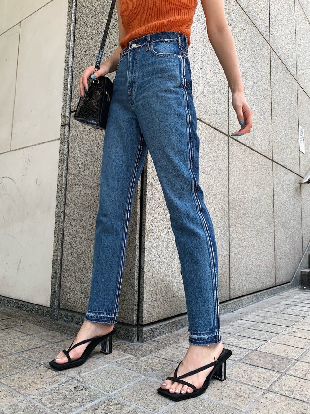 ブルー系のデニムパンツ、ブラック系のサンダル、オレンジ系のニット/セーターを着用したレディースの夏コーディネートの5枚目の写真