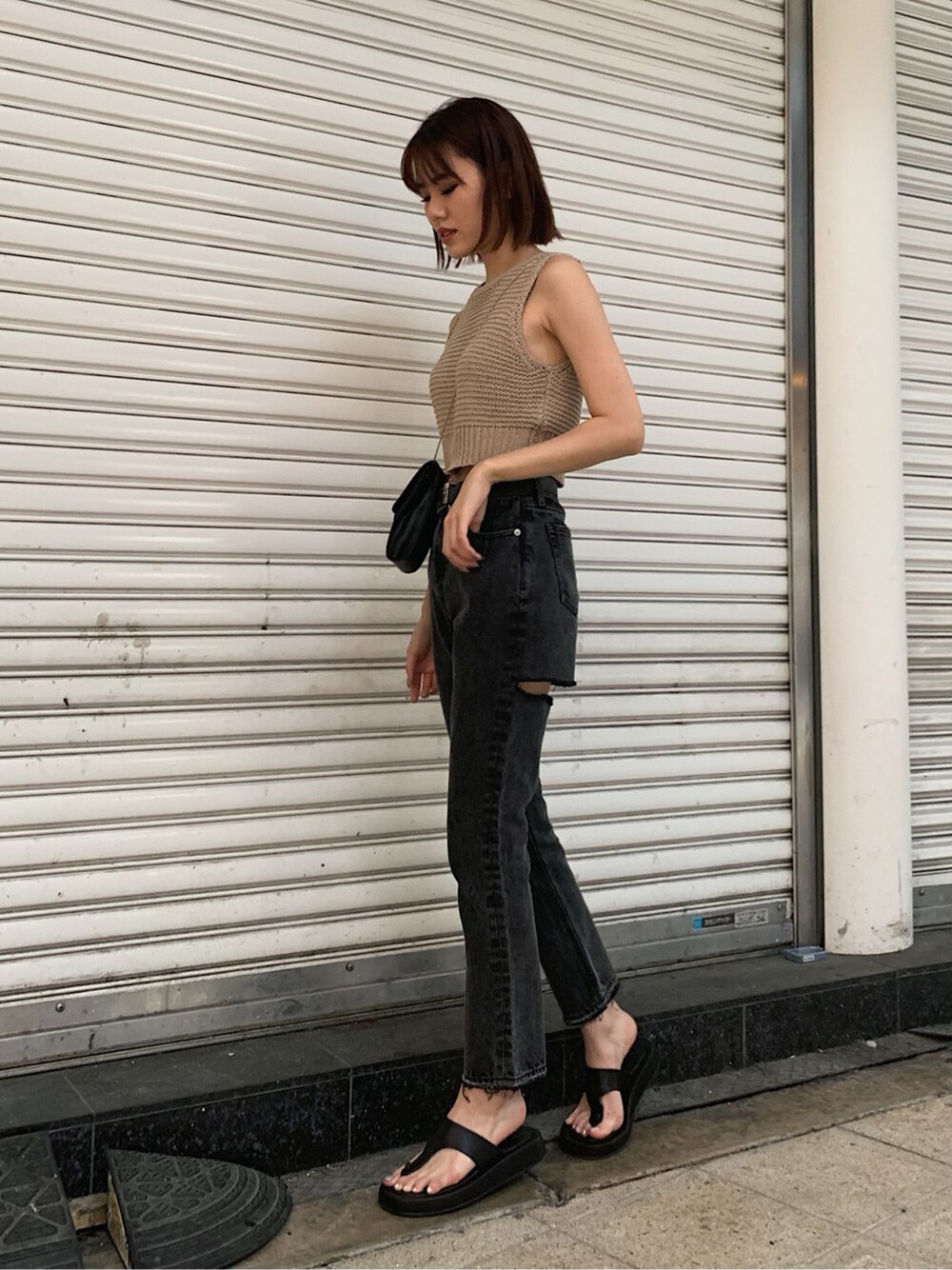 ブラック系のサンダル、ブラック系のデニムパンツ、ベージュ系のタンクトップを着用したレディースの春コーディネートの2枚目の写真