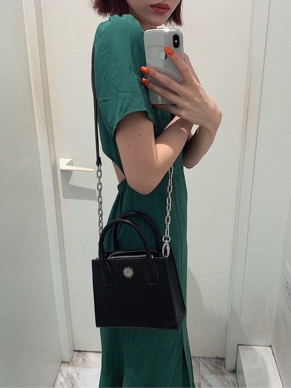 ブラック系のブーツ、ブラック系のショルダーバッグ、グリーン系のワンピースを着用したレディースの春コーディネートの7枚目の写真