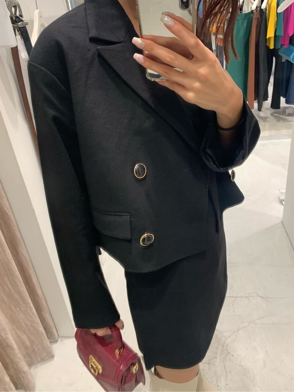 ブラック系のテーラードジャケット、ブラック系のスカート、ホワイト系のブーツを着用したレディースの秋コーディネートの4枚目の写真