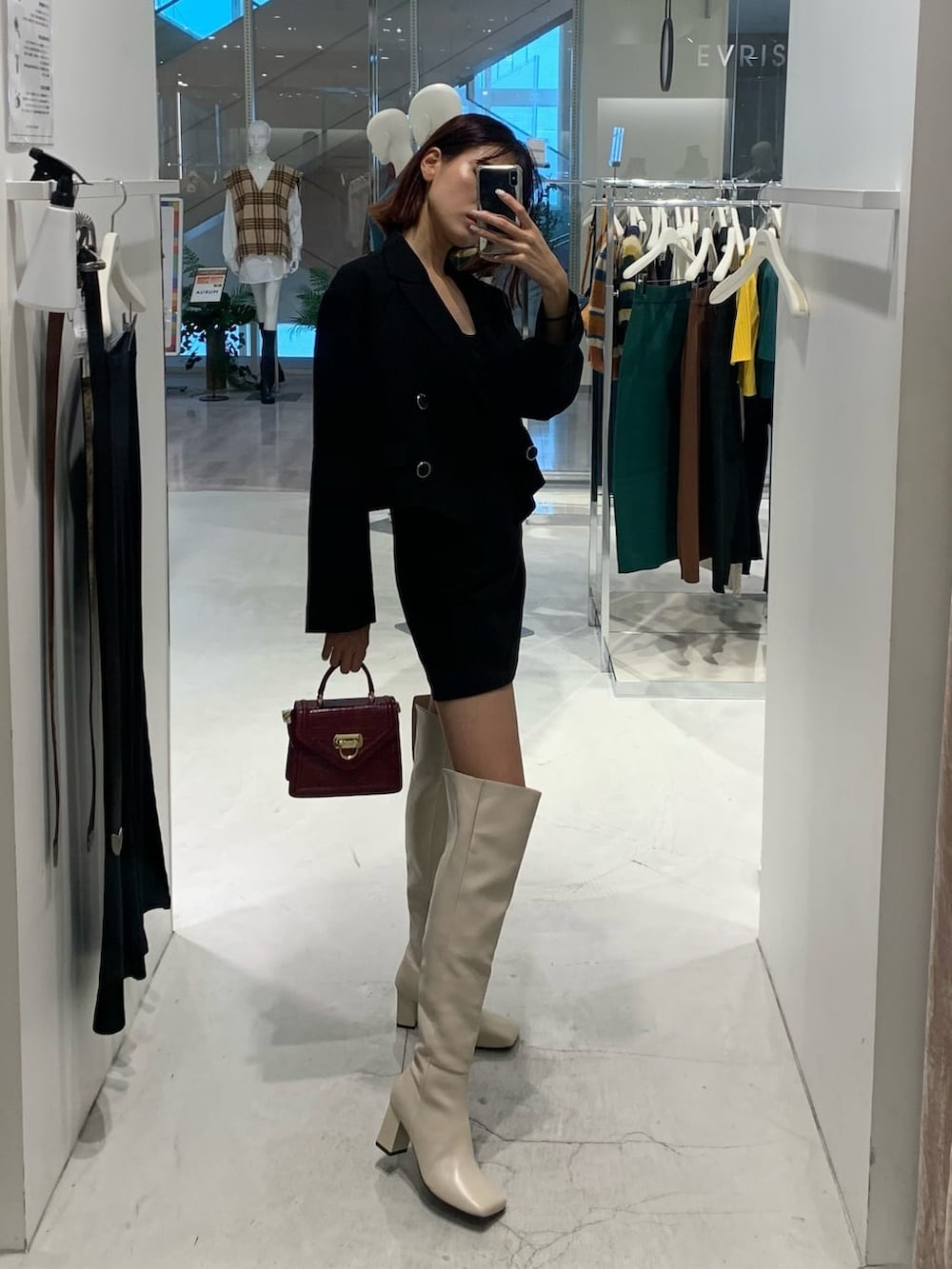 ブラック系のテーラードジャケット、ブラック系のスカート、ホワイト系のブーツを着用したレディースの秋コーディネートの2枚目の写真