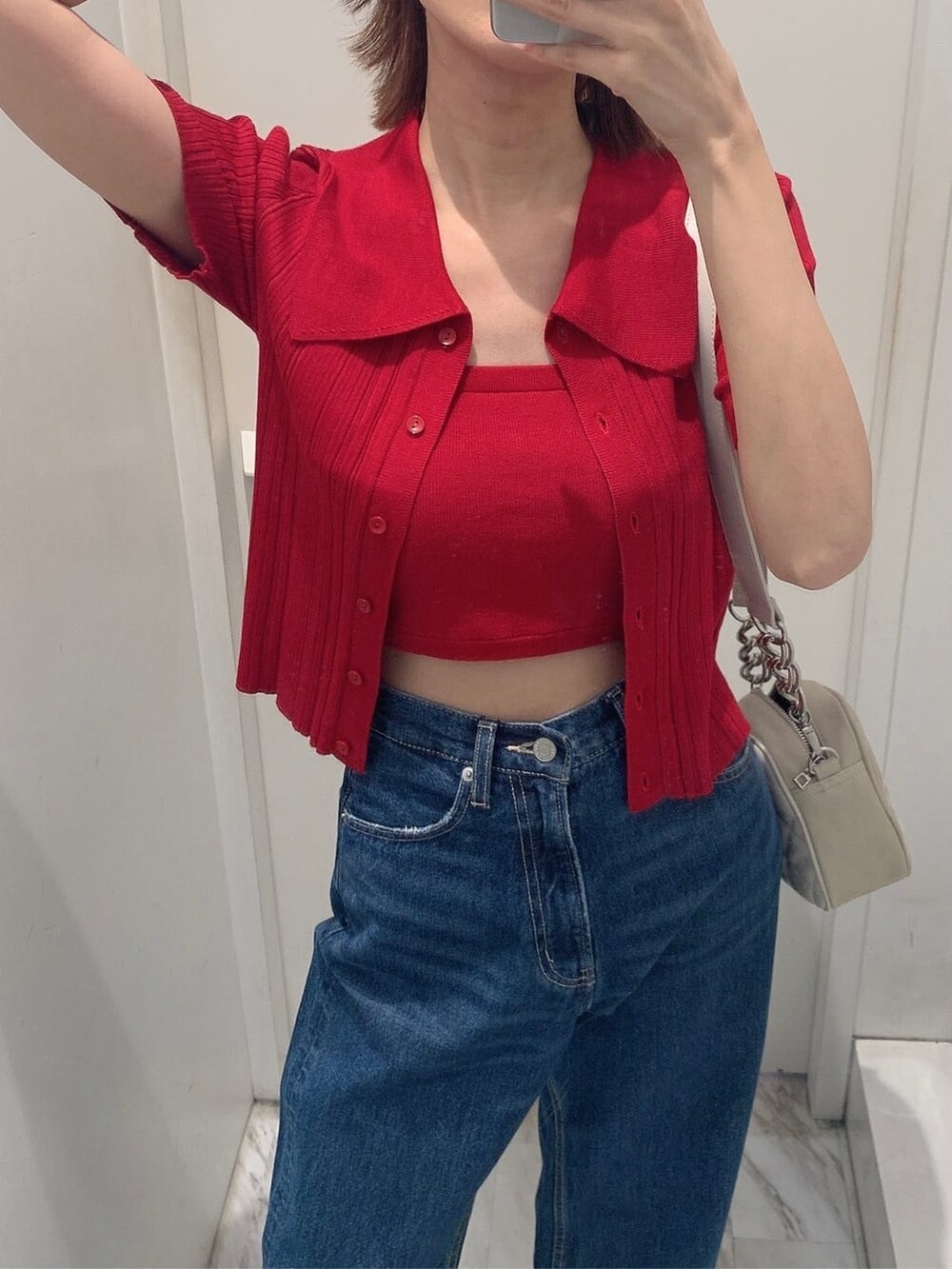 ブルー系のデニムパンツ、ホワイト系のショルダーバッグ、レッド系のニット/セーターを着用したレディースの夏コーディネートの3枚目の写真