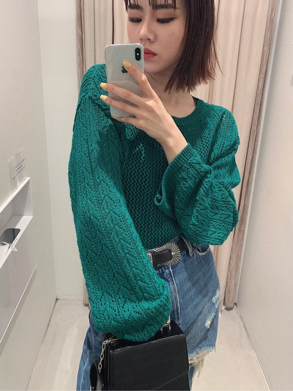 ブラック系のブーツ、ブルー系のデニムパンツ、グリーン系のニット/セーターを着用したレディースの春コーディネートの2枚目の写真