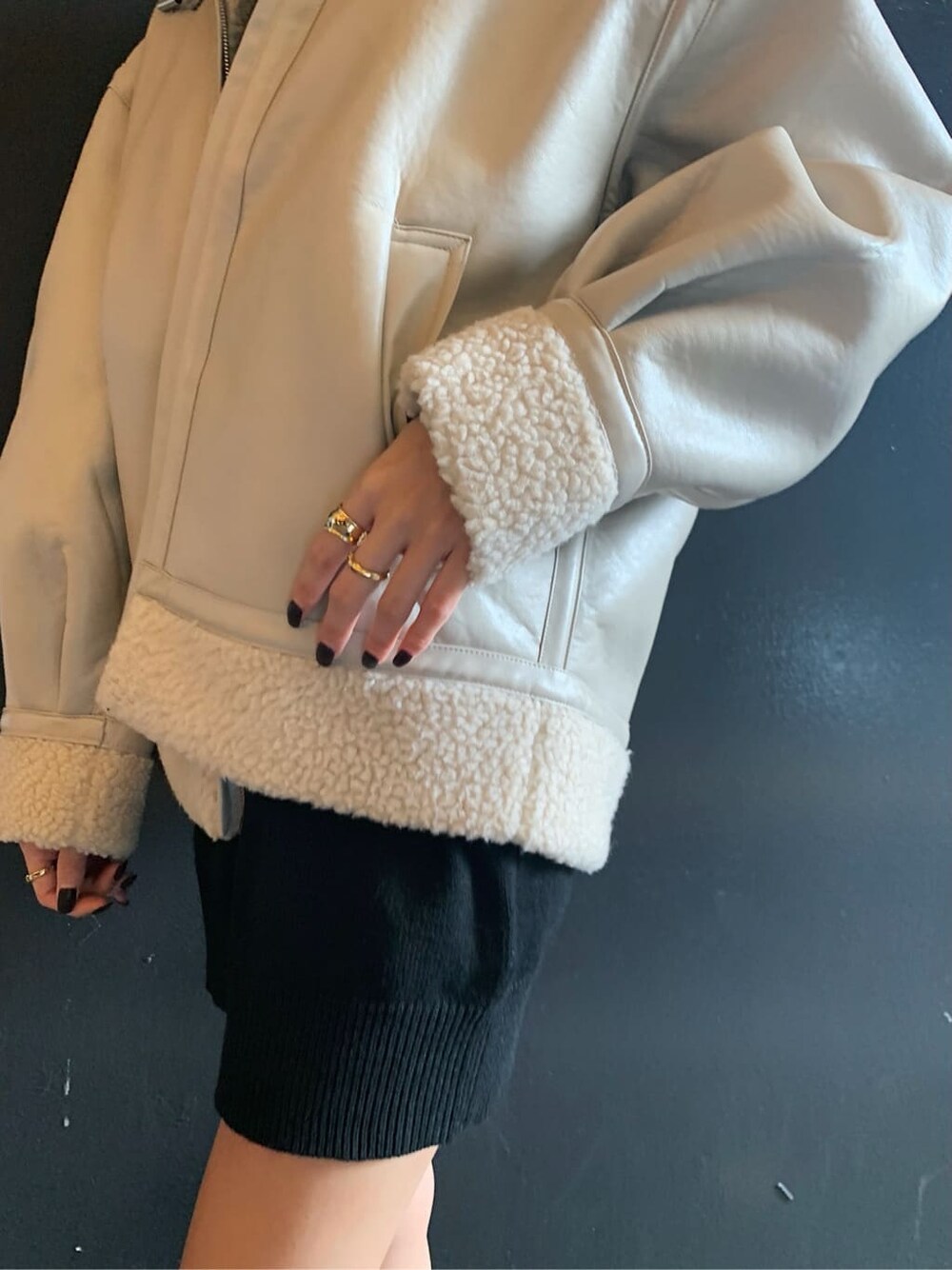 ホワイト系のブルゾン、ブラック系のブーツ、ゴールド系のリングを着用したレディースの冬コーディネートの3枚目の写真