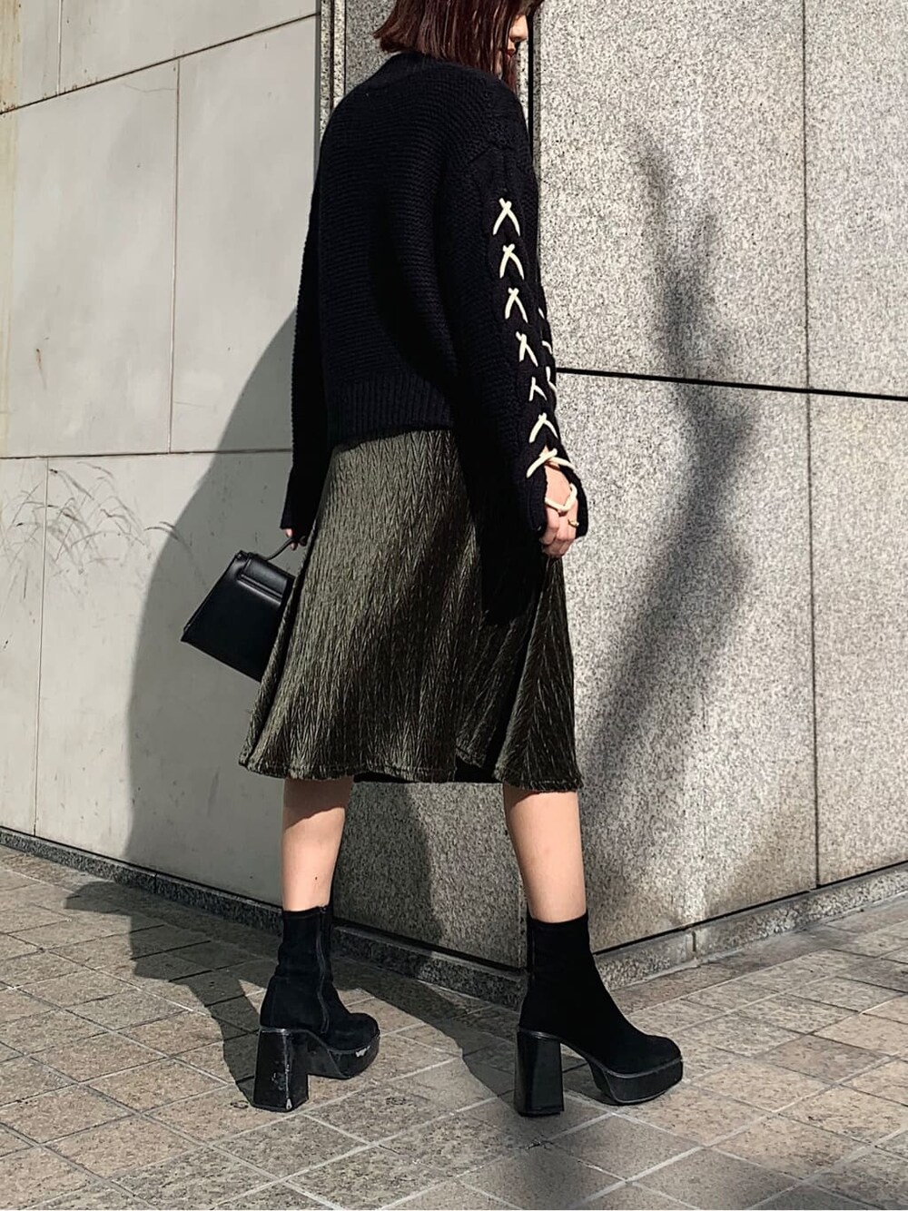 ブラック系のニット/セーター、ブラック系のショルダーバッグ、ベージュ系のワンピースを着用したレディースの冬コーディネートの2枚目の写真