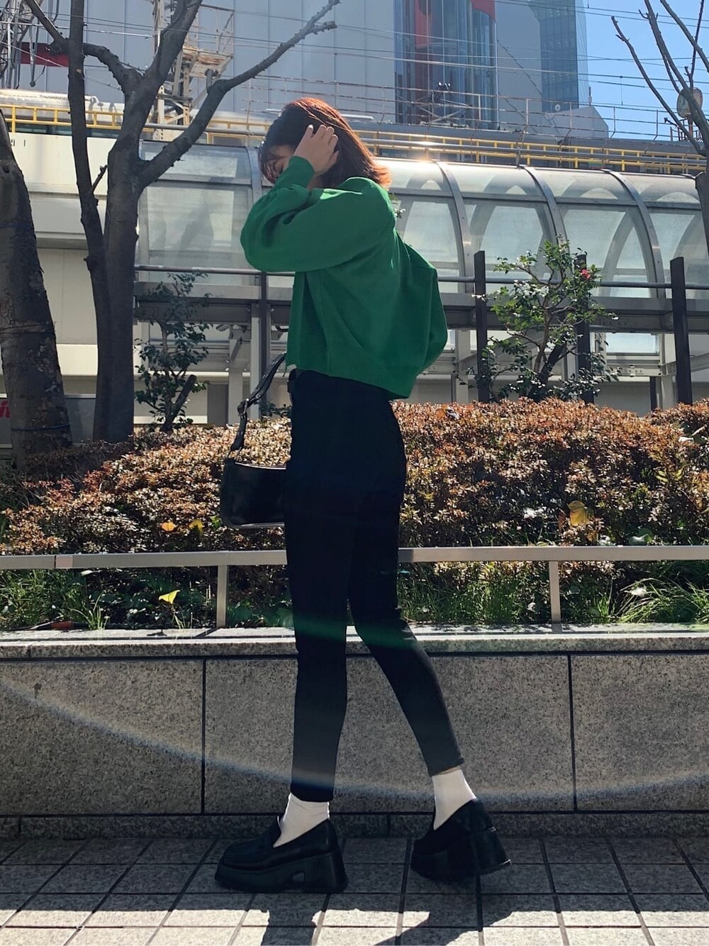 ブラック系のデニムパンツ、ブラック系のローファー、ブラック系のショルダーバッグを着用したレディースの春コーディネートの3枚目の写真